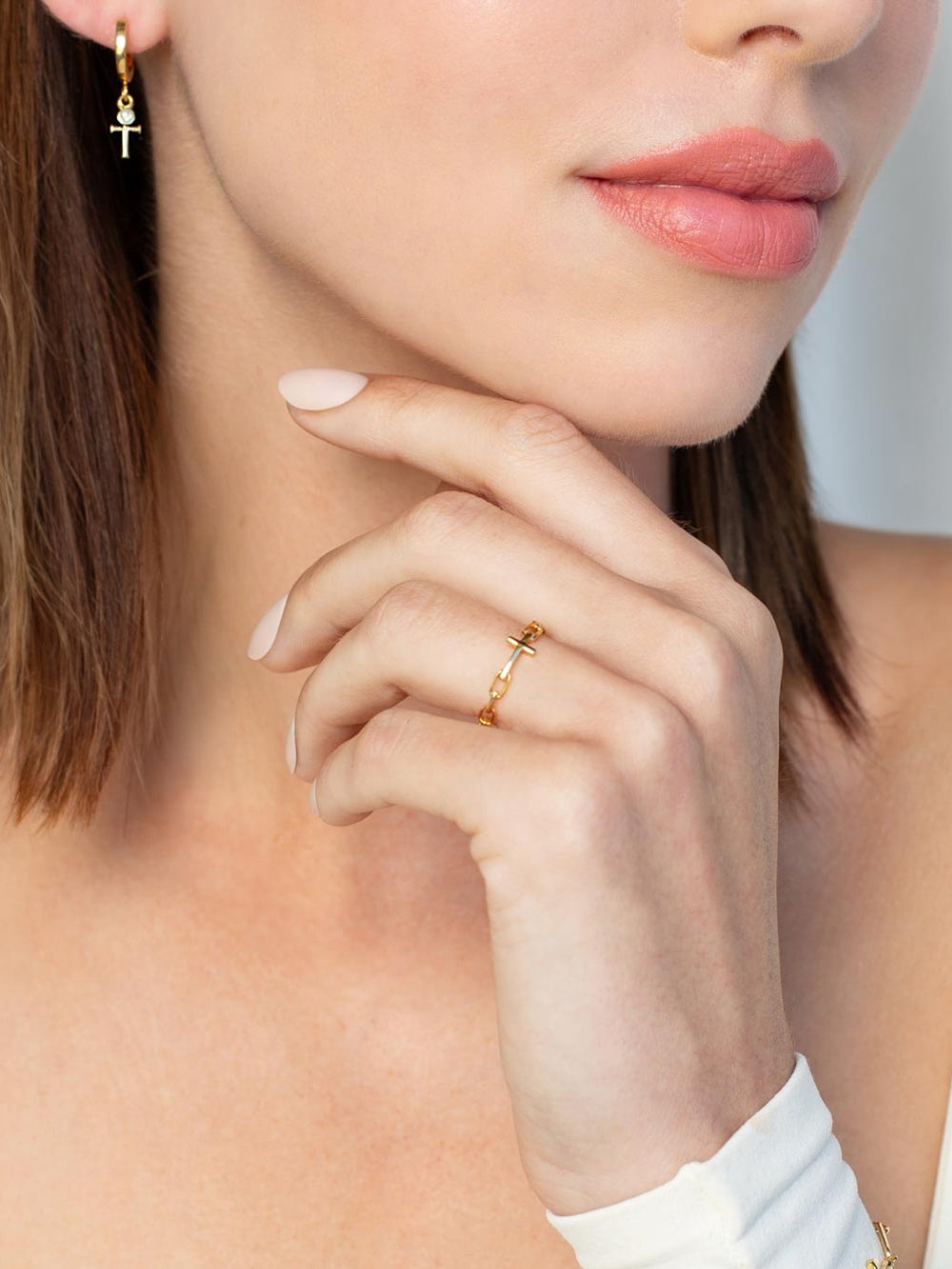 Women's Christian jewelry model is wearing the Mini chain breaker cross ring in 18k gold plated alongside earrings from the Calvary collection.  A timeless baptism gift by Rizen Jewelry.