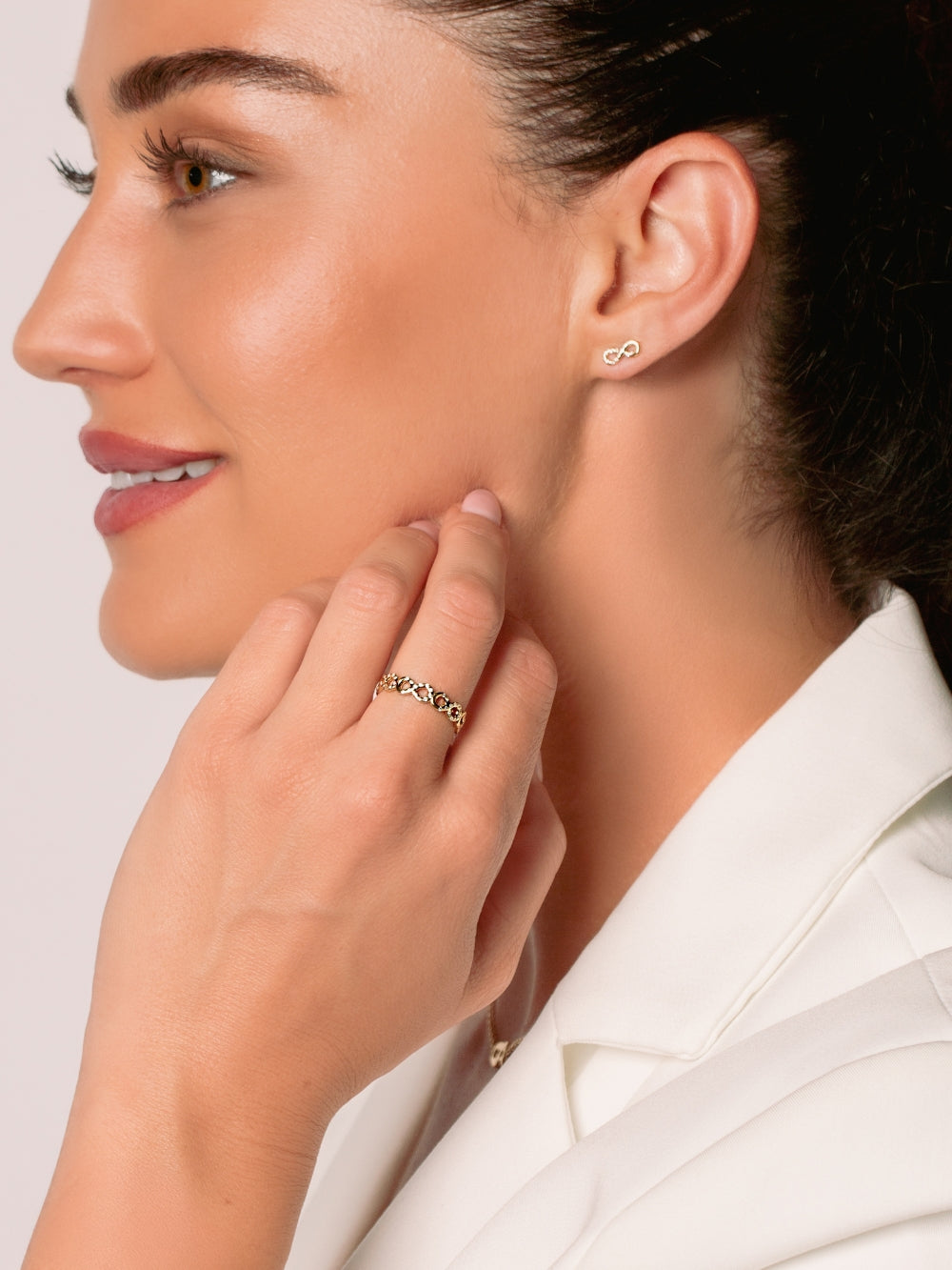 Women's Christian jewelry model is wearing the Infinite hope band ring in 18k gold plated alongside earrings from the Infinite Grace collection.  Inspirational gift for any occasion by Rizen Jewelry.