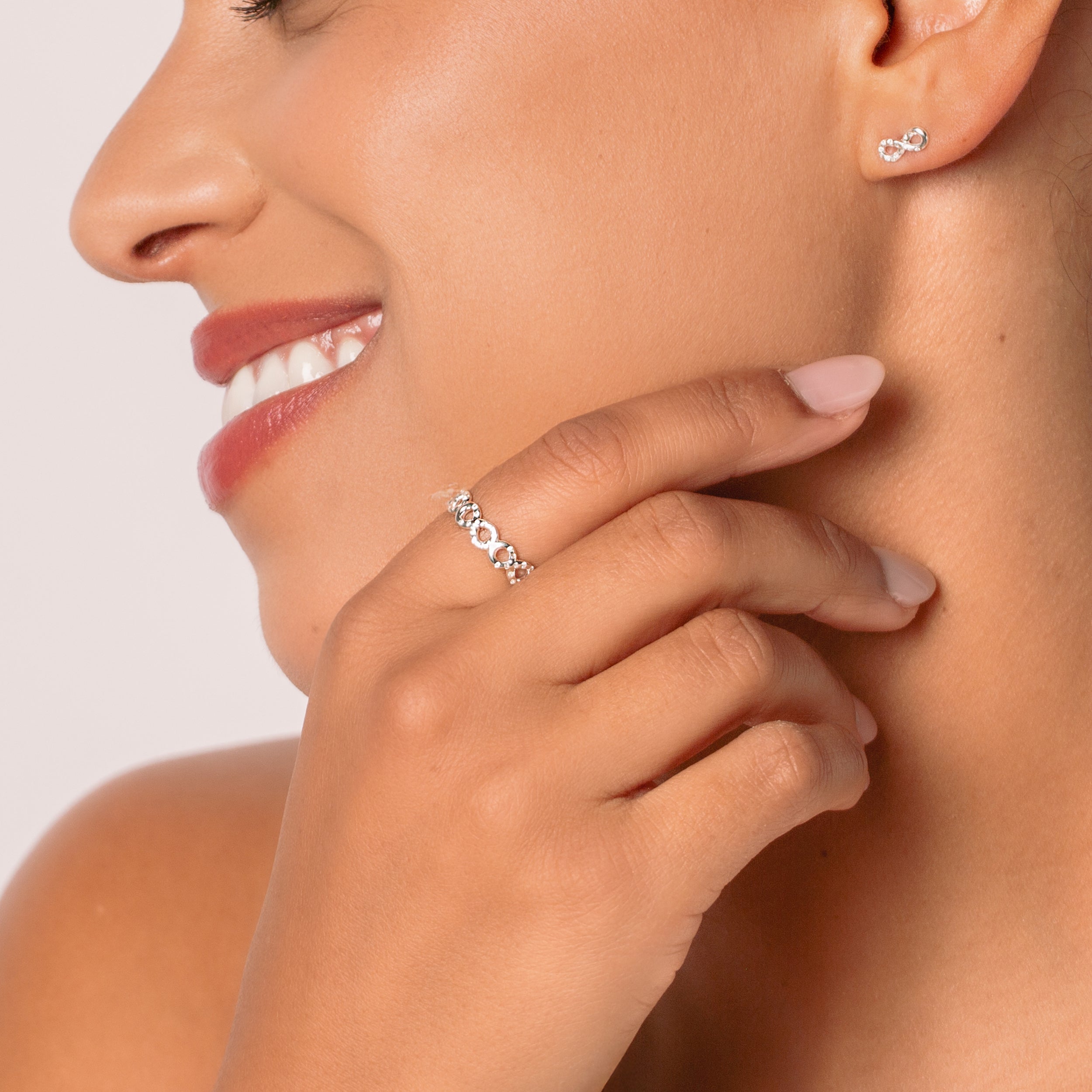 Close-up of a christian woman jewelry model wearing the Sterling silver infinity band ring that showcases a pavé zirconia ichthys nestled within each infinity loop. from the Infinite Grace Collection by Rizen Jewelry.  