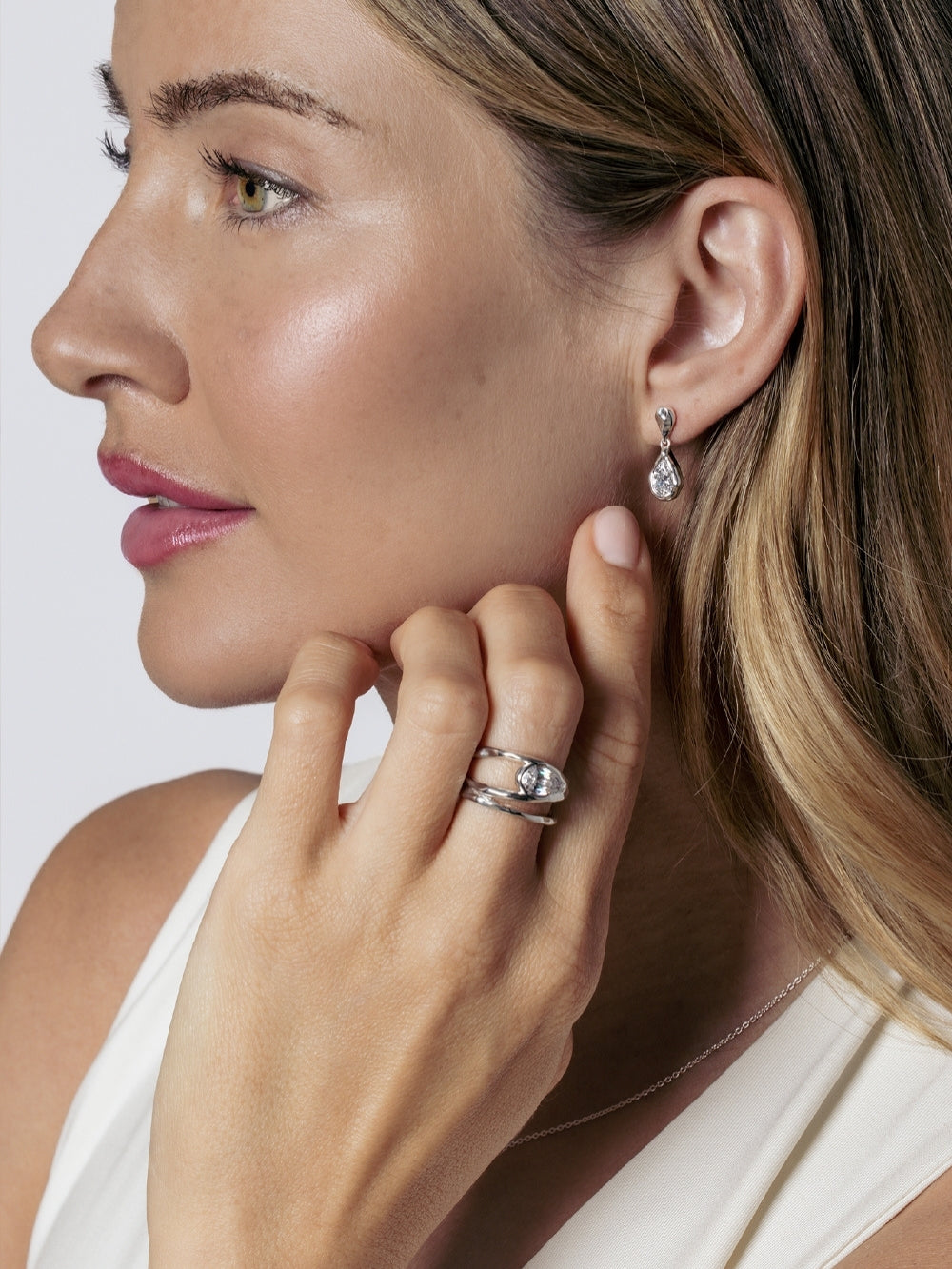 A christian female model is wearing the Rizen Jewelry Solace Teardrop Statemnet Ring crafted in sterling silver along with the matching drop earring.
