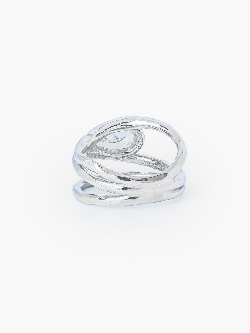 The backside of a tear-shaped simulated diamond ring framed within a hammer-textured setting, crafted with soft, reflective fluid curves. The Rizen Jewelry Solace Teardrop Statemnet Ring is crafted in sterling silver.