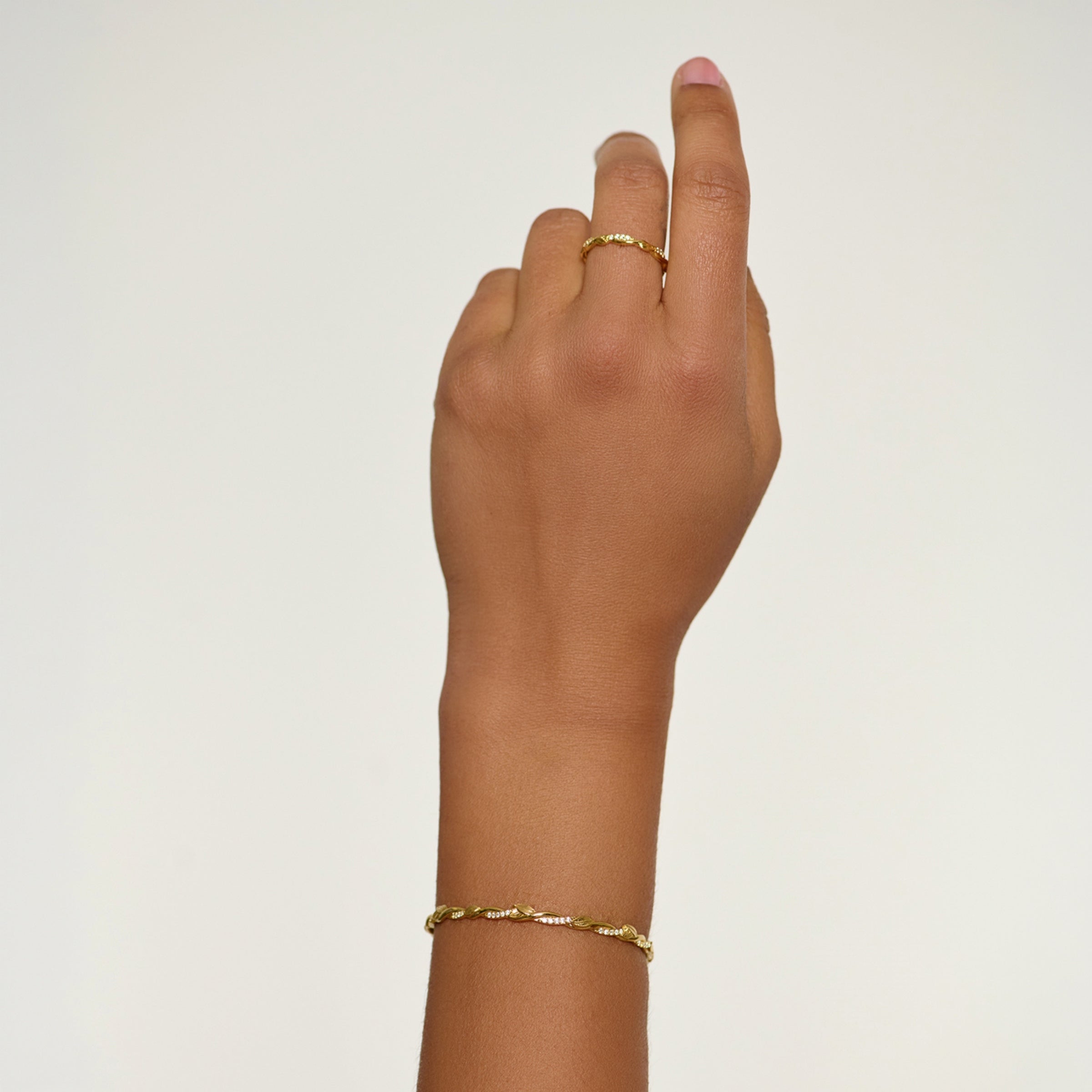 18k gold plated sacred vine band ring with sparkling cubic zirconias and delicate olive leaves intertwined on the band worn by a female christian jewelry model. 