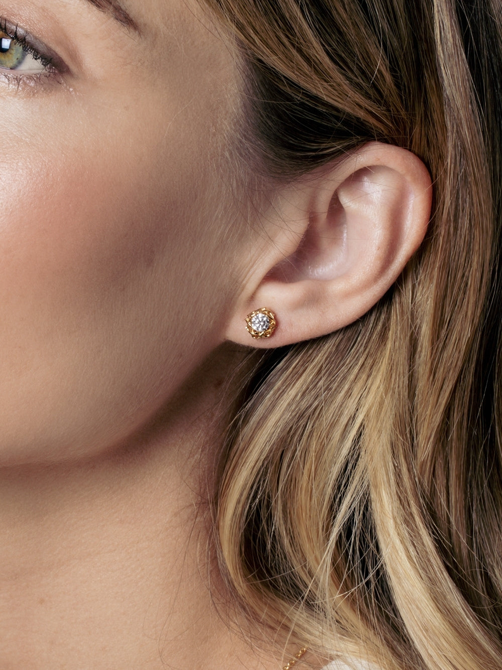 Close-up of a Christian woman wearing the Rizen Jewelry Crown of Thorns stud earrings that feature a brilliant cut round cubic zirconia nestled in an intricately woven crown of thorns setting. 