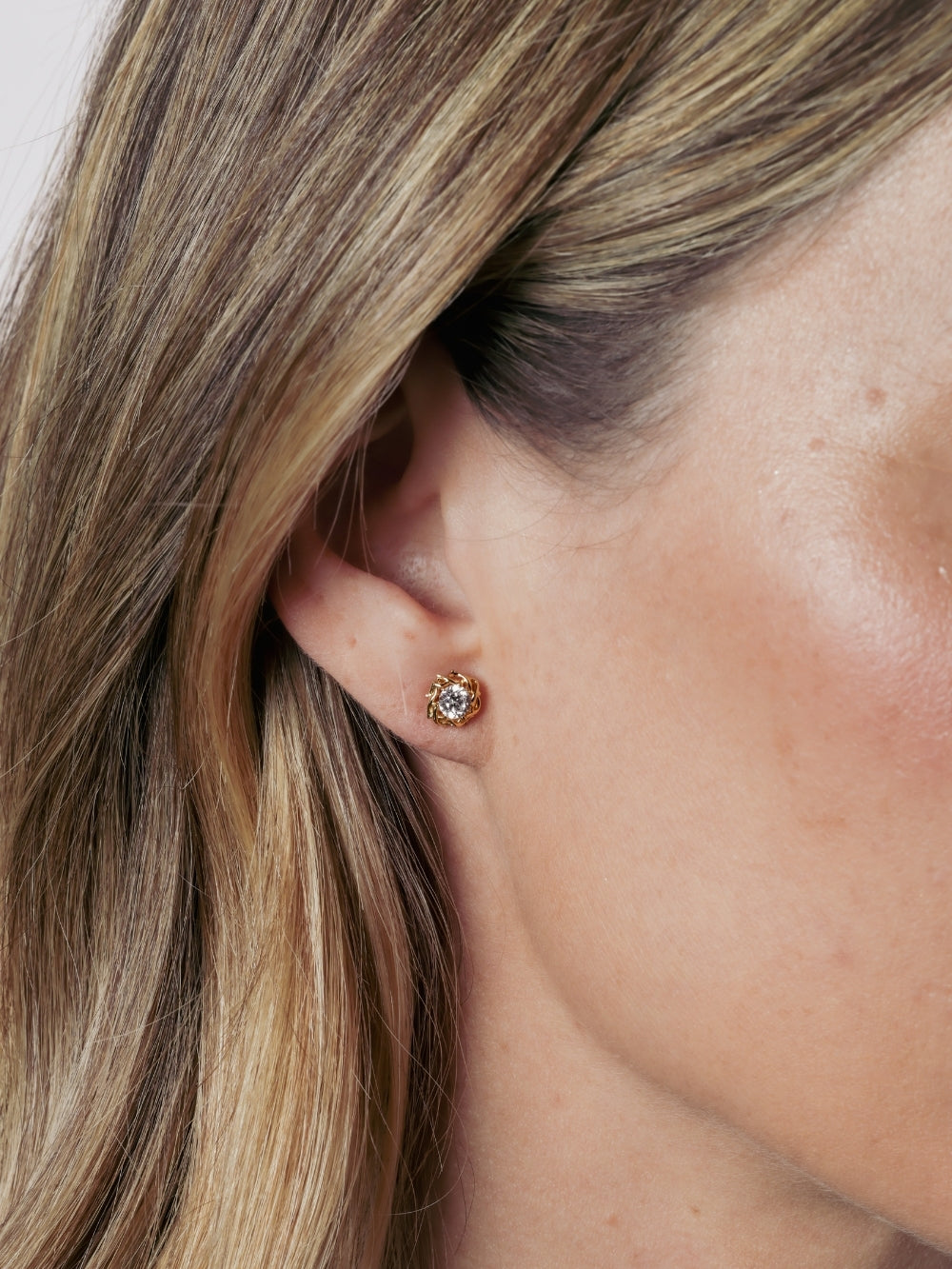 Close-up of a Christian woman wearing the Rizen Jewelry Crown of Thorns stud earrings with a brilliant round cut cubic zirconia nestled within the Crown of Thorns.