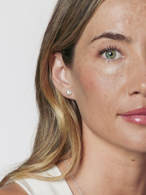 A close up of a Christian female model wearing the Rizen Jewelry Crown of Thorns Stud earrings, that intricately cradle, a round brilliant cut cubic zirconia in the center. 