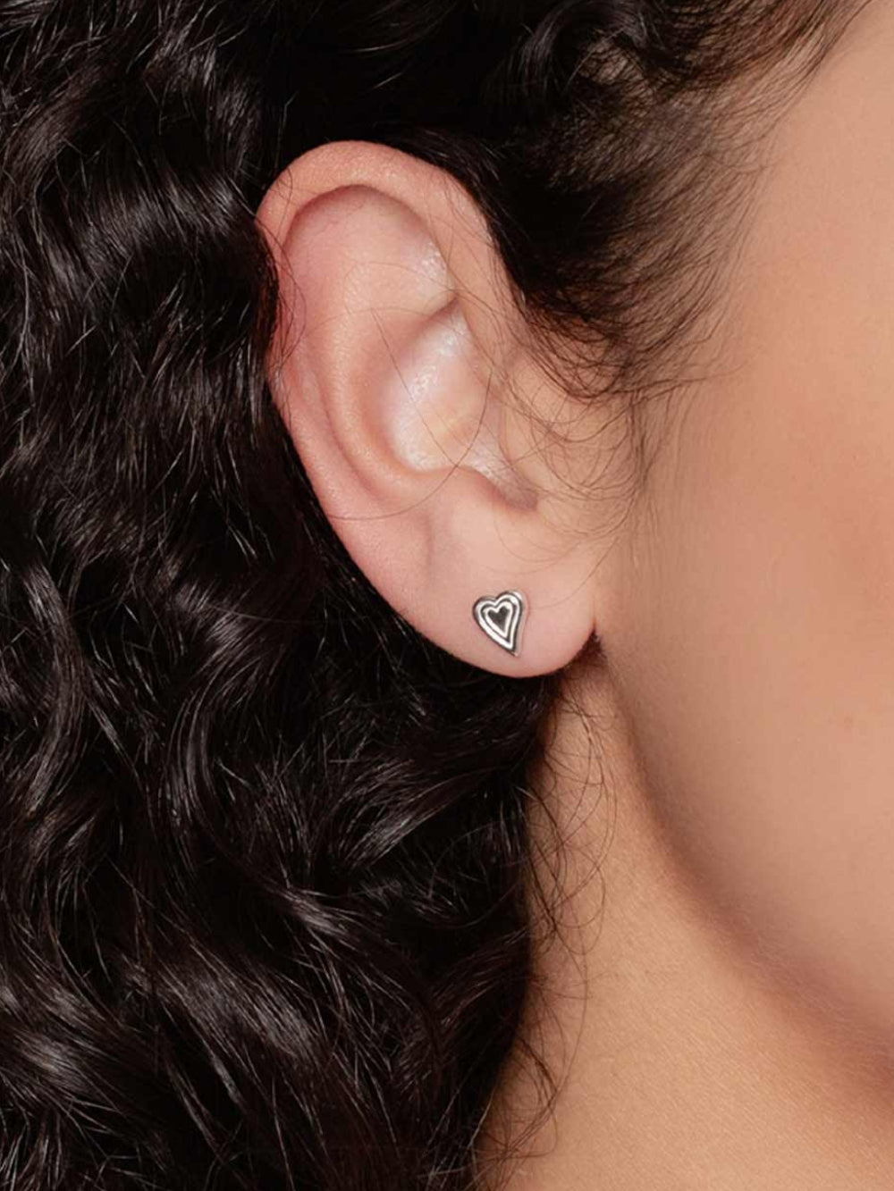 Women's Christian jewelry model is wearing the Emanate love heart earrings in sterling silver from the Infinite Grace collection. A wonderful Christian Jewelry Gift by Rizen Jewelry. 