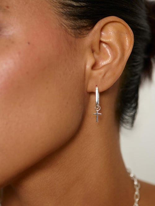Woman's Christian jewelry model wearing the Sleek Sterling Silver Hoop Earrings with Cross Dangle by Rizen Jewelry. 