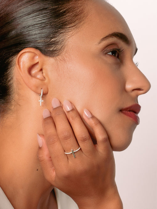 Women's Christian jewelry model is wearing the Luminous cross huggie hoop earrings in sterling silver alongside a ring from the Calvary collection. A wonderful Christian Jewelry Gift by Rizen Jewelry.
