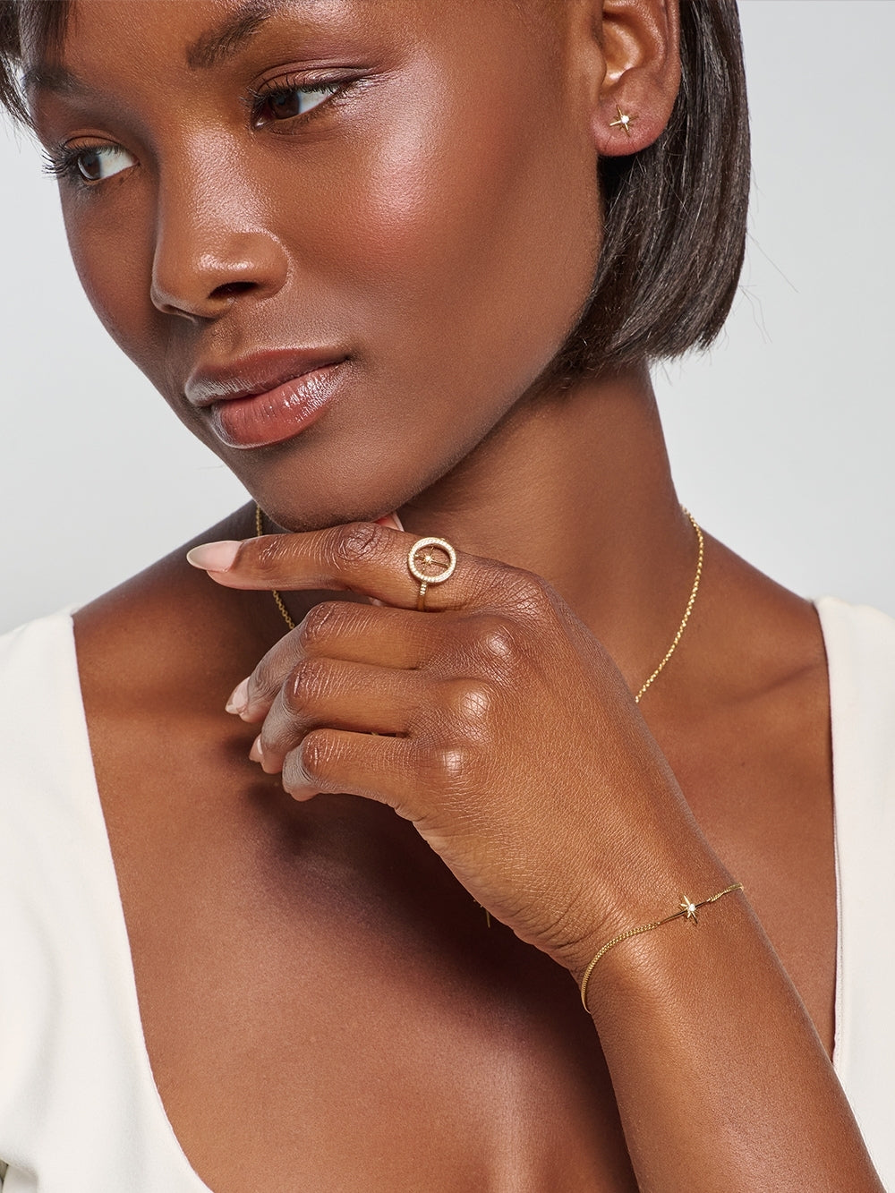 Model wearing the Adoring Star Stud Earrings, radiant gold star studs inspired by the Star of Bethlehem, with the matching bracelet, ring and necklace deisgned by Rizen Jewelry.