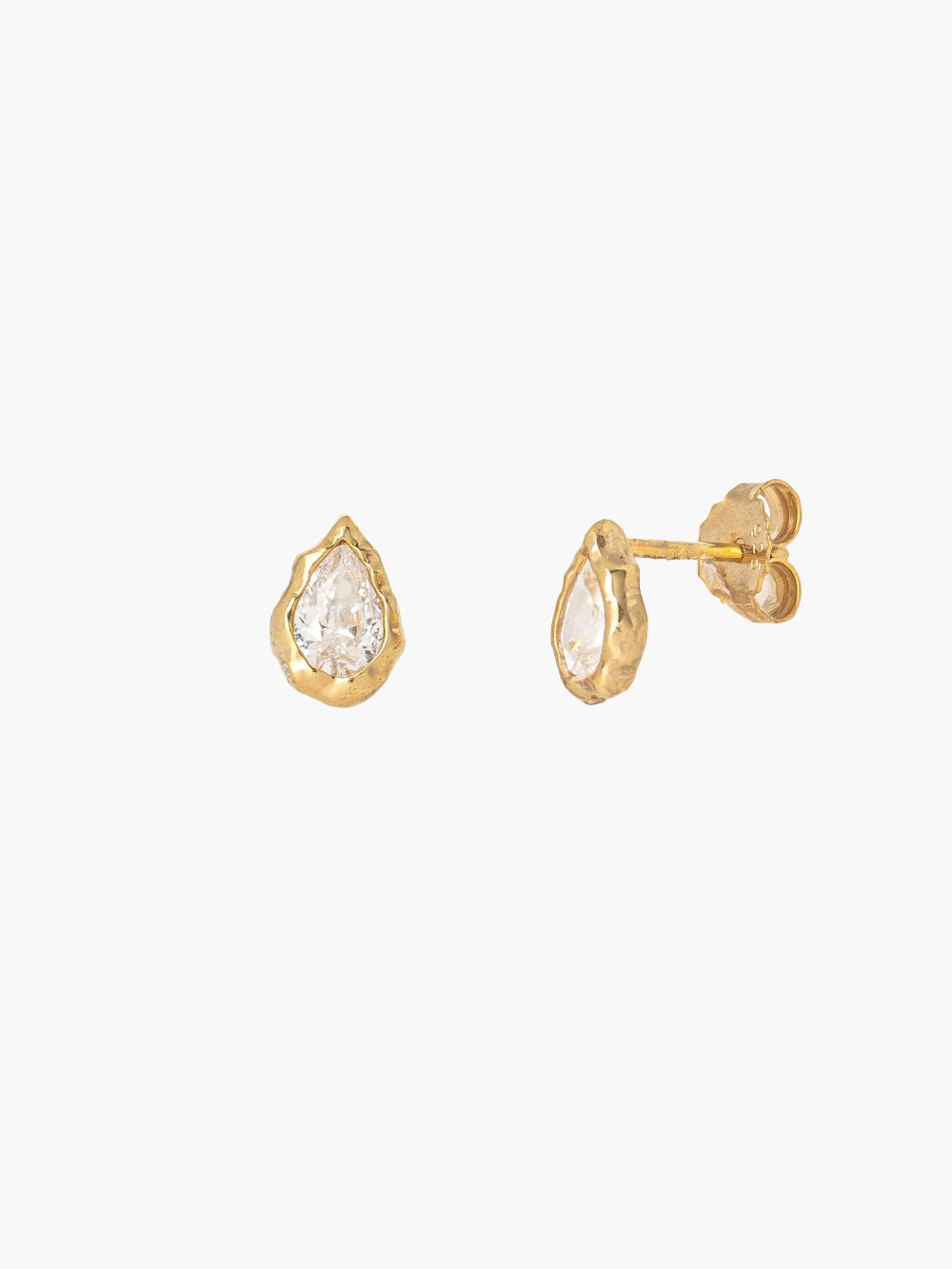 A pair of the Rizen Jewelry gold Solace Tear Stud Earrings. Feature teardrop shapped earrings with clear faceted simulated diamonds, nestled within a fluid hammered texture. One earring is facing forward to show the stone, and the other is turned to the side showing the post and backing.