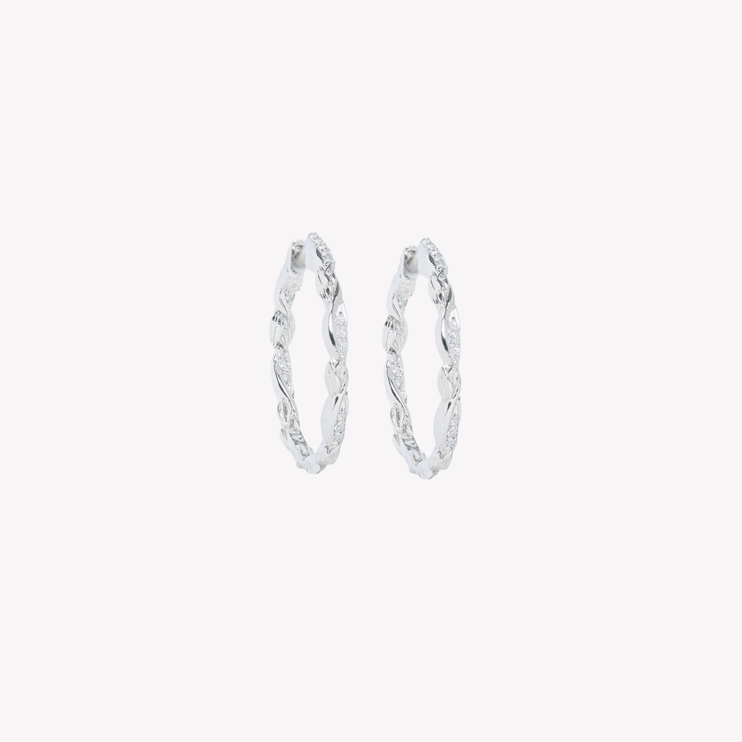 Sterling silver one-inch hoop earrings feature delicate olive leaves and micro-set zirconia along the inner and outer curves. Finished with a seamless hinge closure for effortless comfort.
