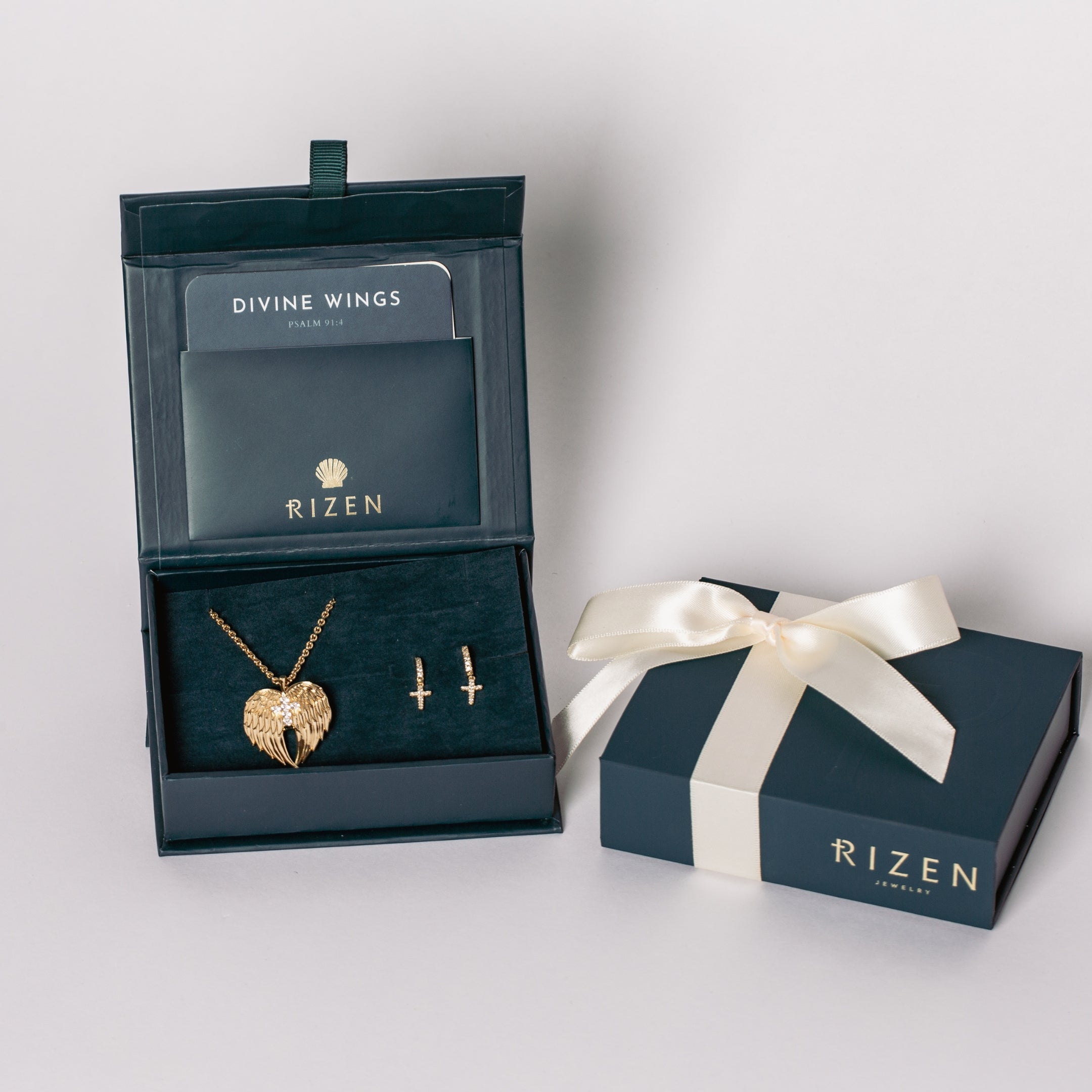 18K gold vermeil Divine Wings jewelry set featuring the heart shaped angel wing necklace with a sparkly pair of the Luminous Cross Huggie Hoop Earrings Featured in the Rizen Jewelry Gift Box.