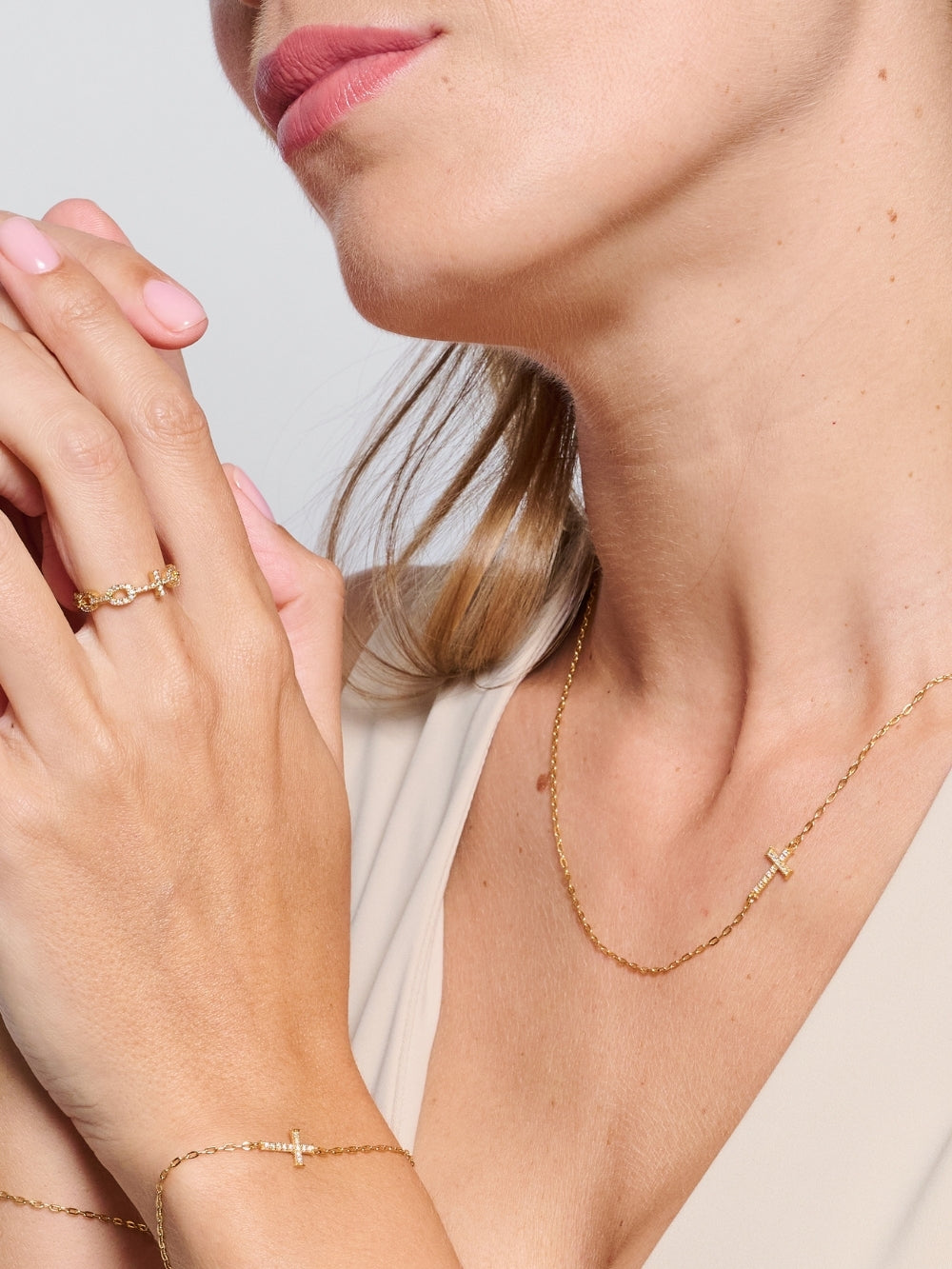 Female model wearing the Delicate Cross Chain Breaker Necklace, an 18k gold-plated pavé cross pendant resting at the collarbone
