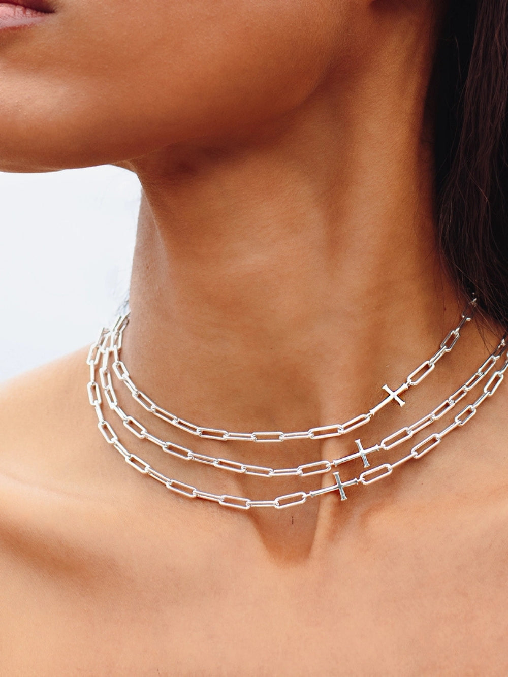 Women's Christian jewelry model wearing three Silver Paper Clip Chain Breaker Cross Necklace in Sterling Silver by Rizen Jewelry. 