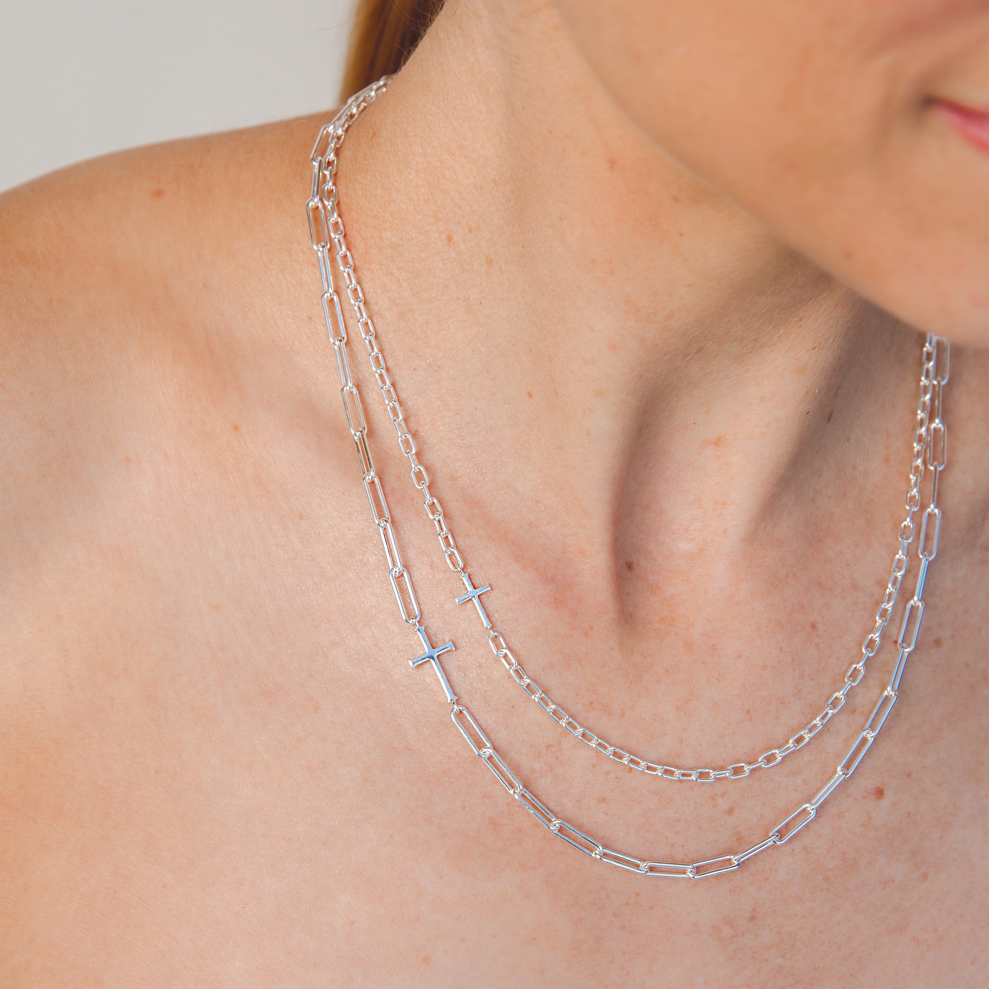 Mini Chain Breaker Cross Necklace in sterling silver from the calvary collection by Rizen Jewelry layered with original Chain Breaker Cross Necklace on a Christian Woman's Neck. 