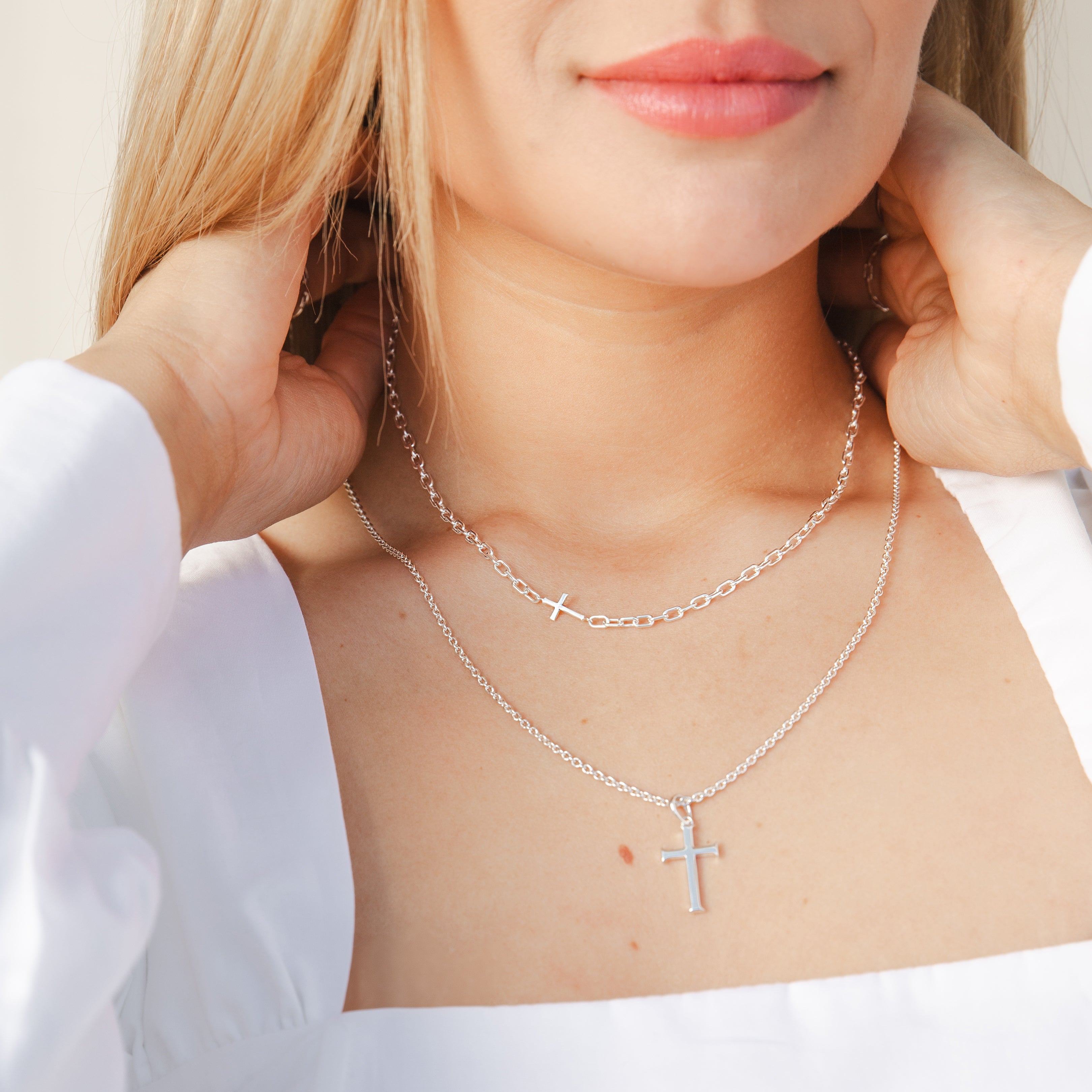 Mini Chain Breaker Cross Necklace in sterling silver from the calvary collection by Rizen Jewelry being put on a Christian Woman wearing the Large Cross Pendant. 