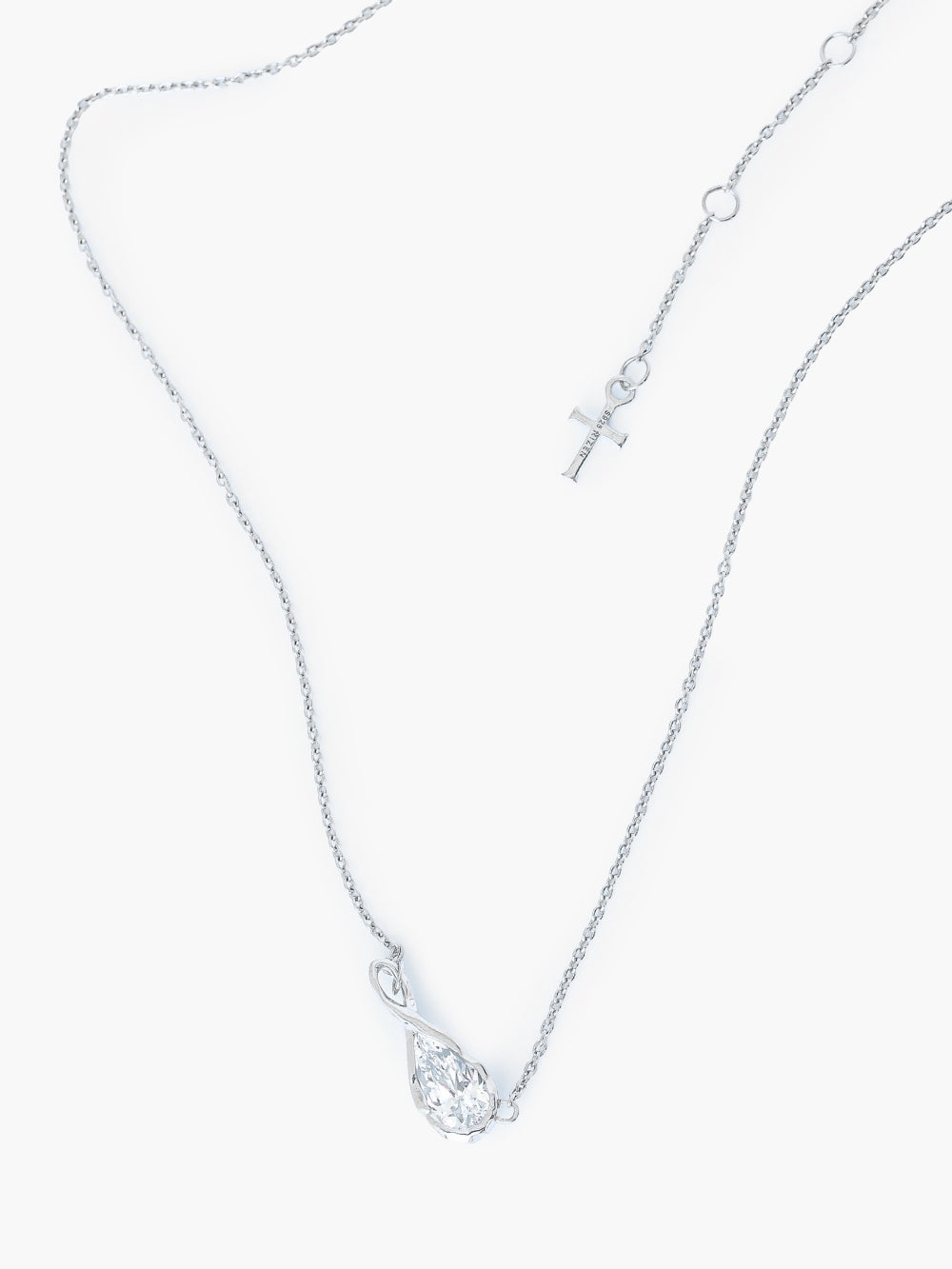 Rizen Jewelry Solace Teardrop Necklace features a silver infinity pendant necklace with a clear teardrop-shaped simulated diamond, on a delicate cable chain with the signature Rizen Cross Pendant Tag displayed against a solid off-white background.