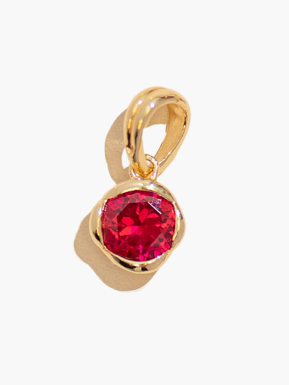 Close-up of the Ruby Fully Known Prayer Pendant by Rizen Jewelry features a round brilliant-cut light lab ruby stone is cradled in 18k gold plating over sterling silver setting. The pendant symbolizes passion, redemption, value, and the month of July.