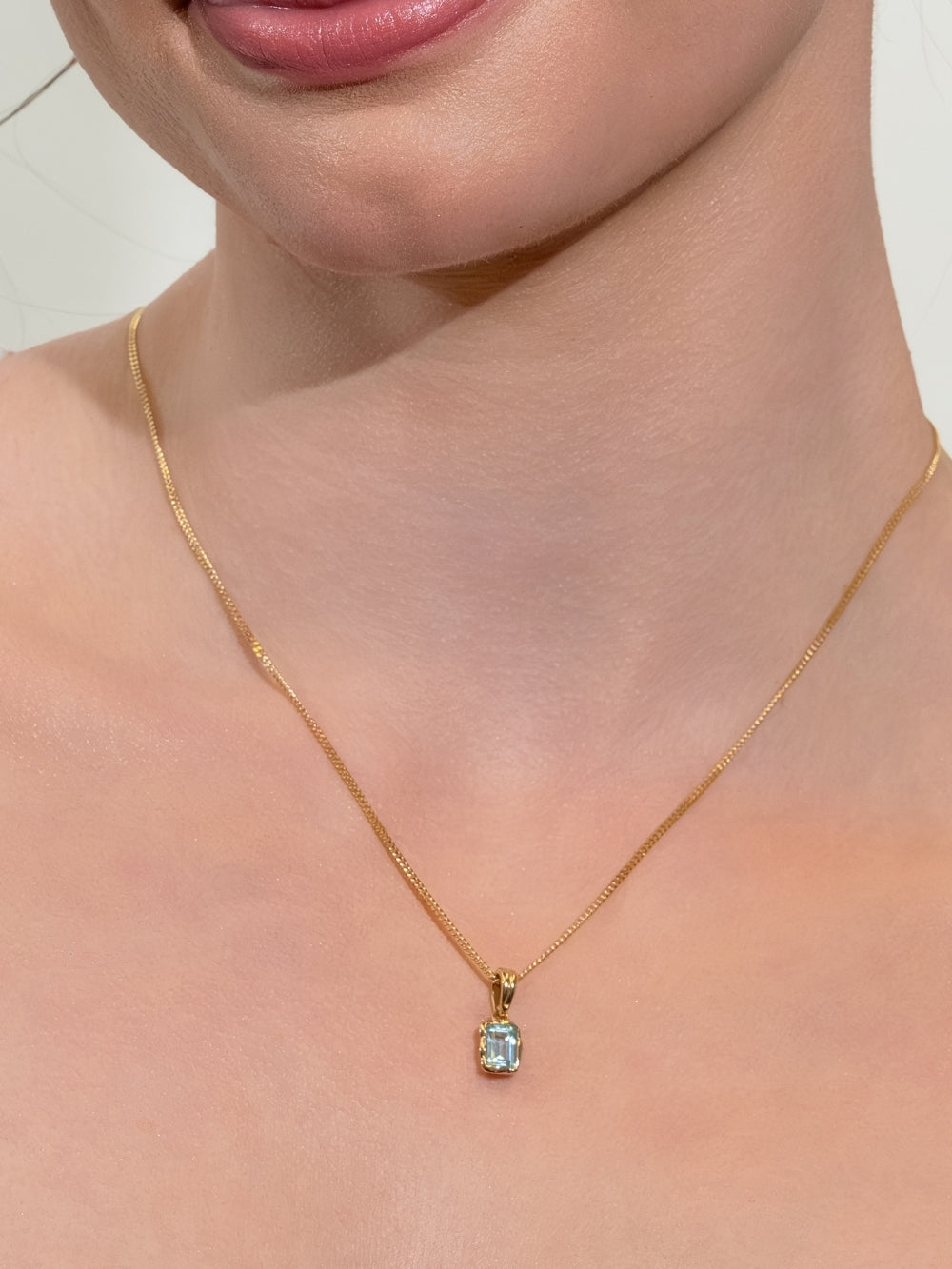 Women's Christian jewelry model wearing a sleek curb chain featuring the Sky Blue Topaz Fully Known Prayer Pendant and gold. 