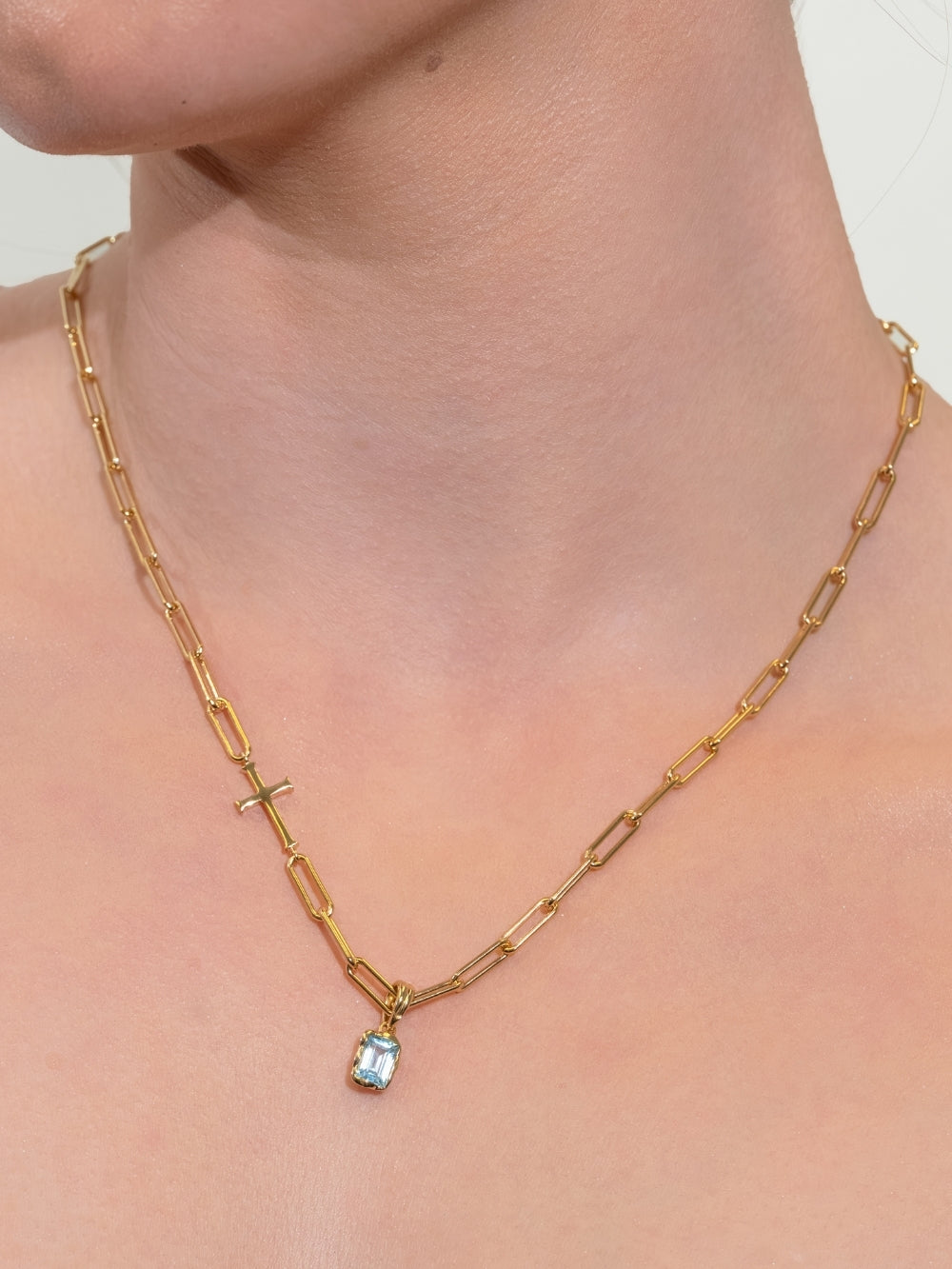 Women's Christian Jewelry model wearing the Sky Blue Topaz Fully Known Prayer Pendant featured on the Rizen Jewelry Chain Breaker Cross Necklace in gold finish.