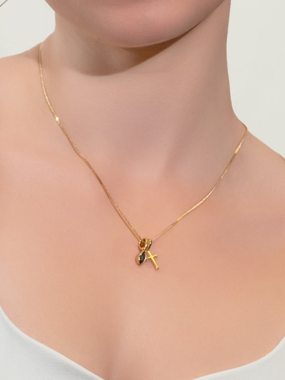 Woman's Christian jewelry model wearing the London Blue Topaz Fully Known Prayer Pendant with the small gold cross pendant by Rizen Jewelry. 