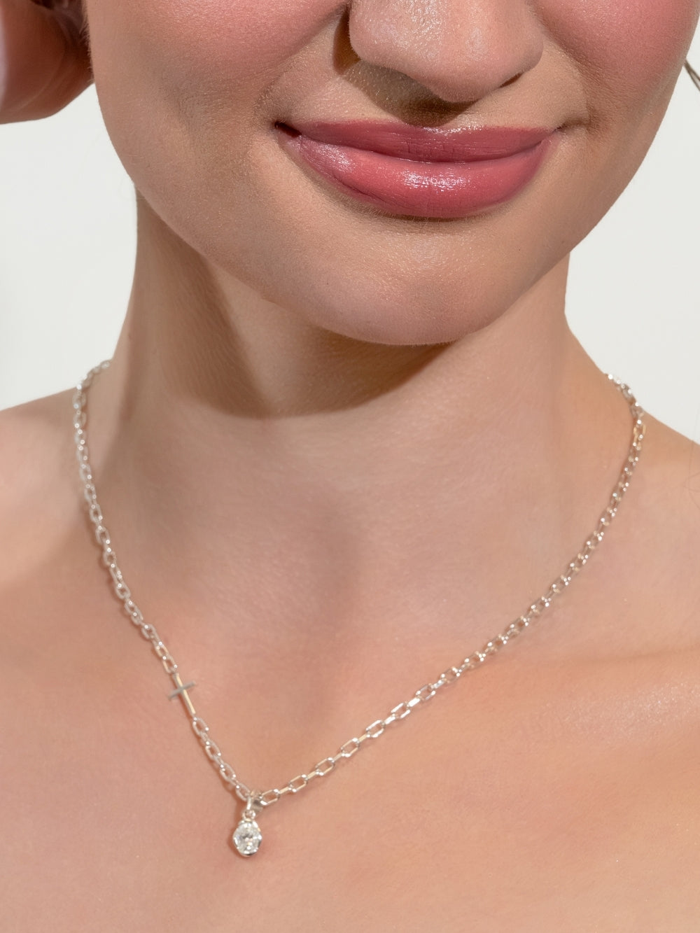 Woman's Christian jewelry model wears the White Sapphire Fully Known Prayer Pendant by Rizen Jewelry features An oval brilliant cut white sapphire stone is cradled in 18k gold plating over sterling silver setting. The pendant symbolizes Purity, New Identity, Innocence, and the month of April.