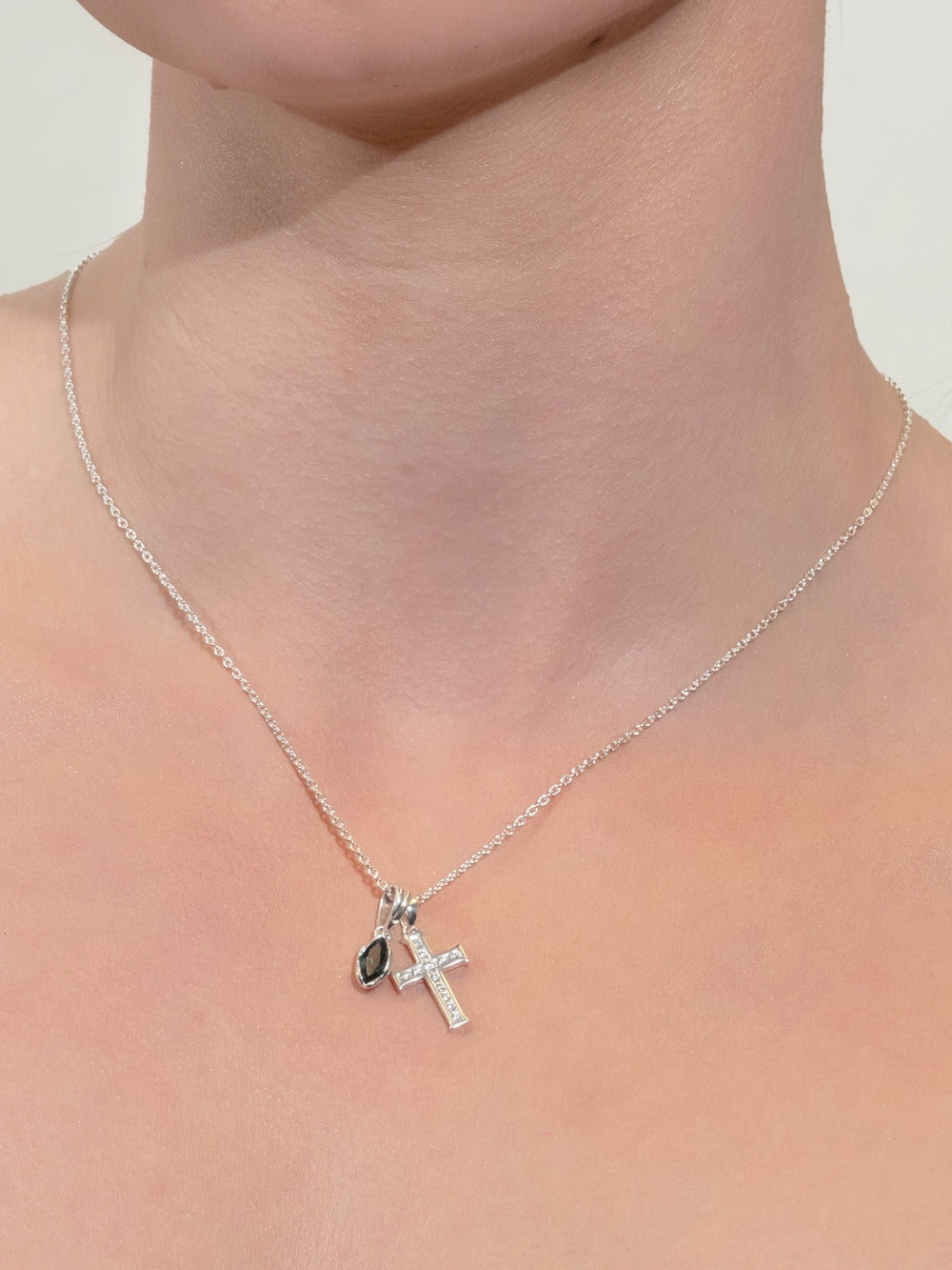 Women's Christian jewelry model wearing the London blue Topaz Fully Known Prayer pendant added to the Luminous Cross necklace in silver by Rizen Jewelry.