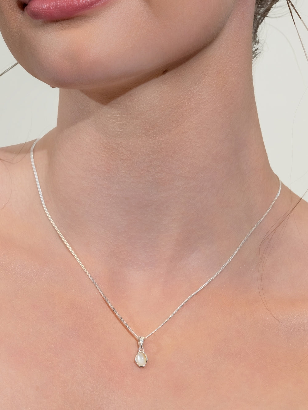 Woman's Christian Jewelry model wears the White Mother of Pearl Fully Known Prayer Pendant by Rizen Jewelry features an oval cabochon Mother of Pearl stone  cradled in sterling silver setting. The pendant symbolizes Transformation, Sacred, Beauty, and the month of June.