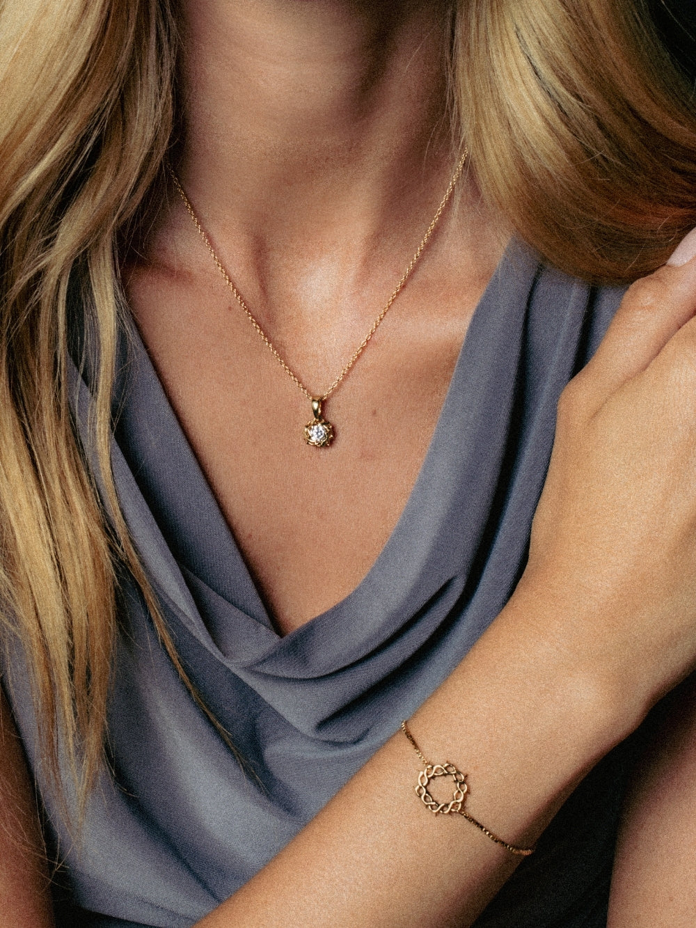A close-up lifestyle shot of a Christian woman wearing the Rizen Jewelry Crown of Thorns pendant on a delicate cable chain with a matching Crown of Thorns bracelet. 