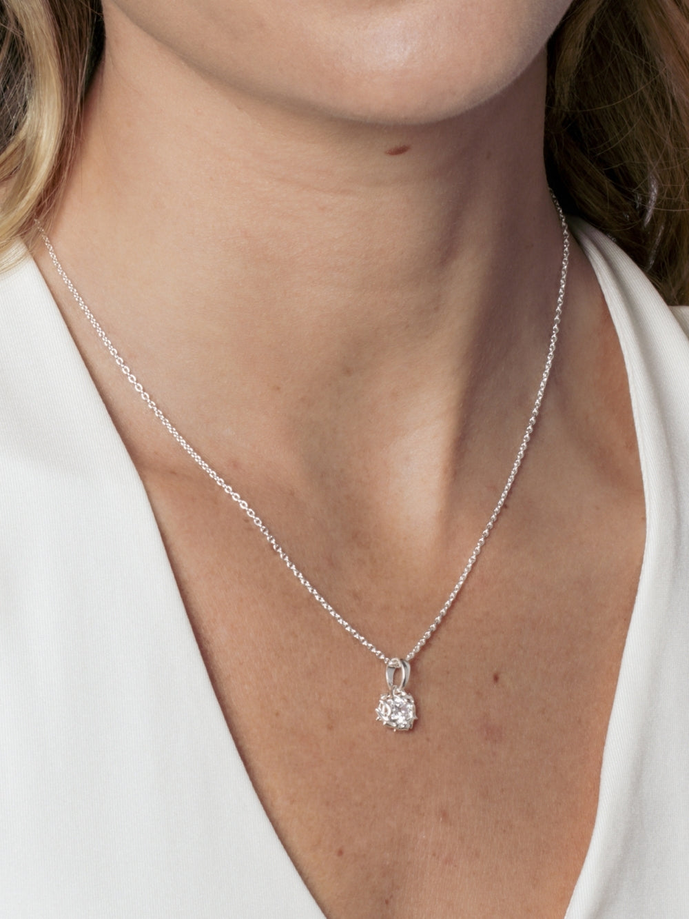 Close up of a female Christian jewelry model wearing the Rizen Jewelry Crown of Thorns pendant on a dainty silver cable chain. 