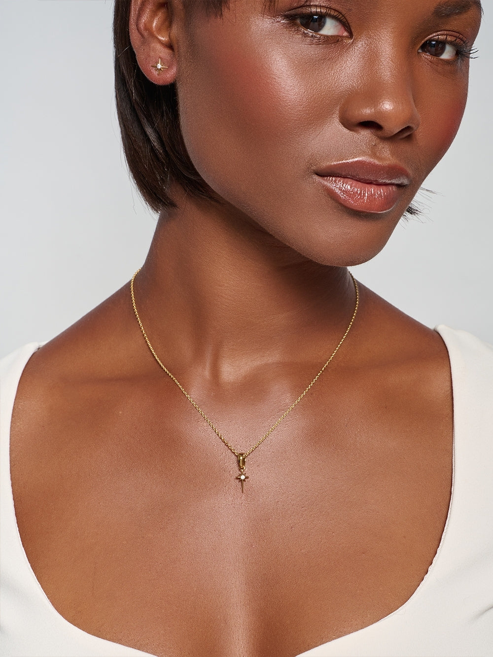 Model wearing the Adoring Star Pendant, a radiant gold Star of Bethlehem pendant on a cable chain necklace.