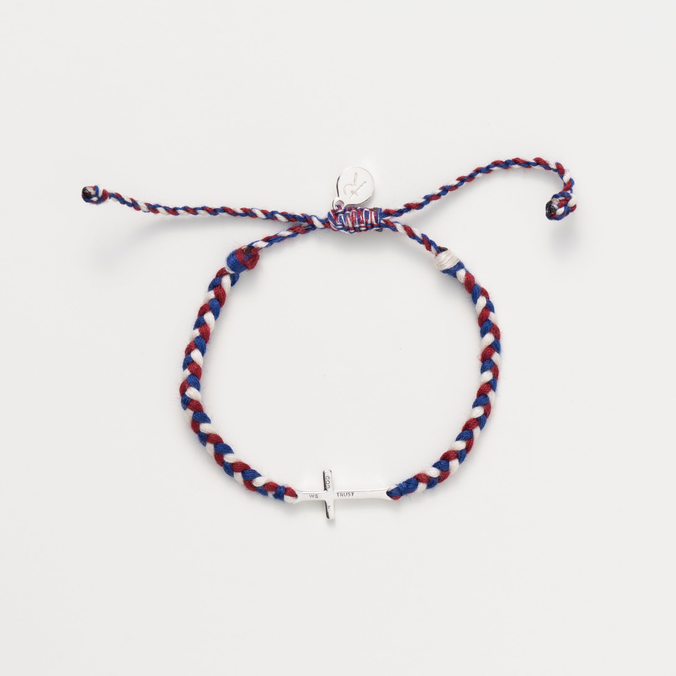 silver cross bracelet hand braided in red, white, blue cotton cord, engraved "WE TRUST IN GOD" with Rizen Jewelry and Made 4 Ministry round disc tag. 