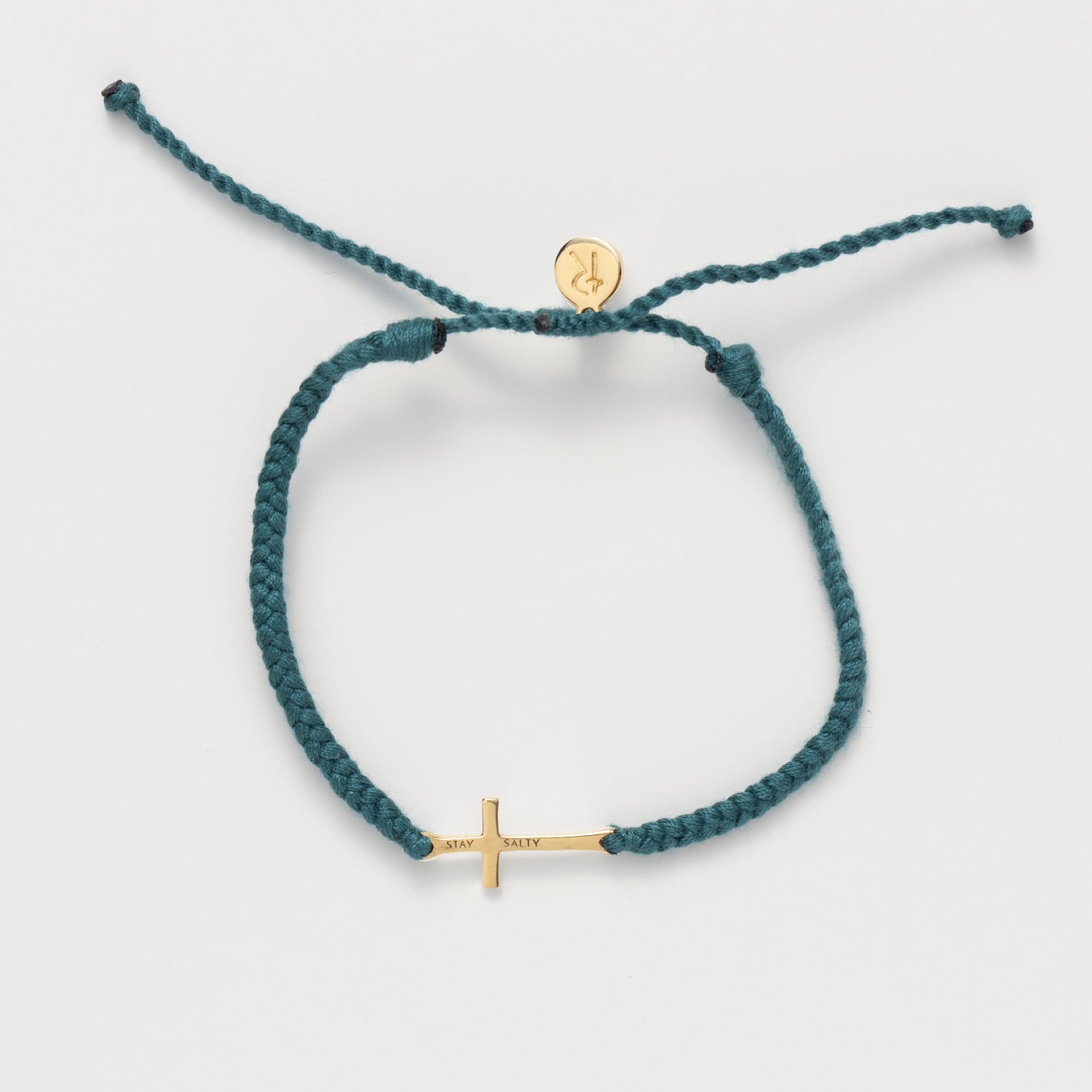 Cross bracelet engraved STAY SALTY set on a naturally dyed azure blue hand-braided, cotton cord friendship bracelet with a gold finish from the Made4Ministry Collection by Rizen Jewelry. 