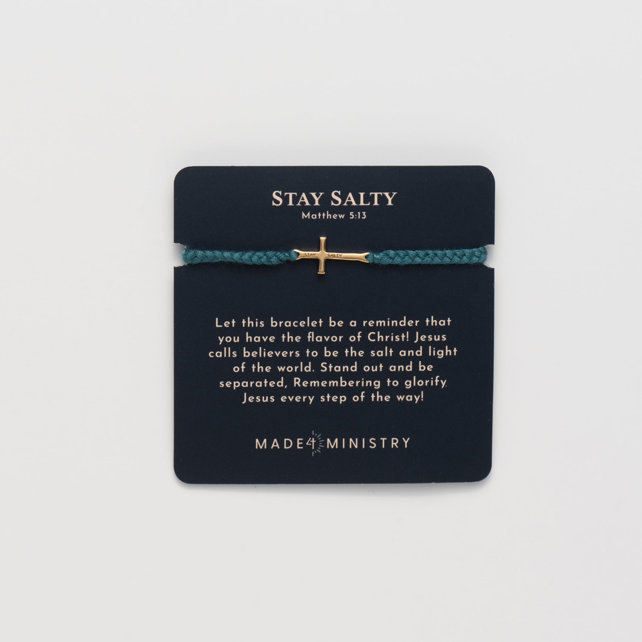 Cross bracelet engraved STAY SALTY set on a naturally dyed azure blue hand-braided, cotton cord friendship bracelet with a gold finish from the Made4Ministry Collection by Rizen Jewelry.  Featured on a devotion card. 