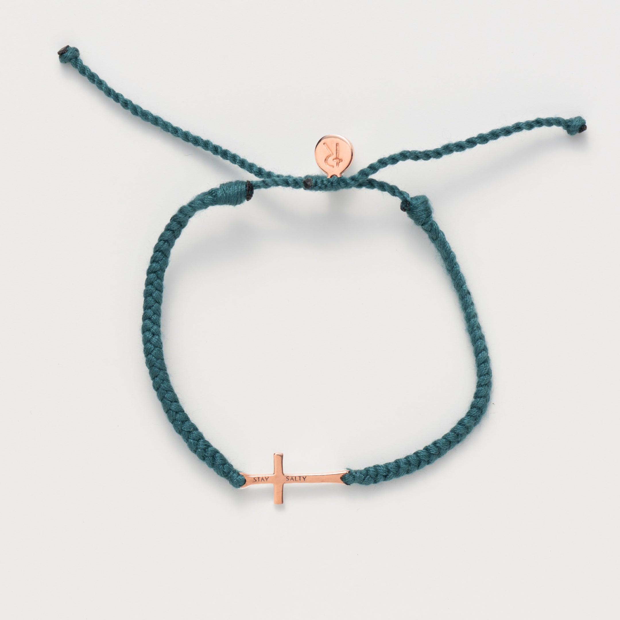 Cross bracelet engraved STAY SALTY set on a naturally dyed azure blue hand-braided, cotton cord friendship bracelet with a  rose gold finish from the Made4Ministry Collection by Rizen Jewelry. 