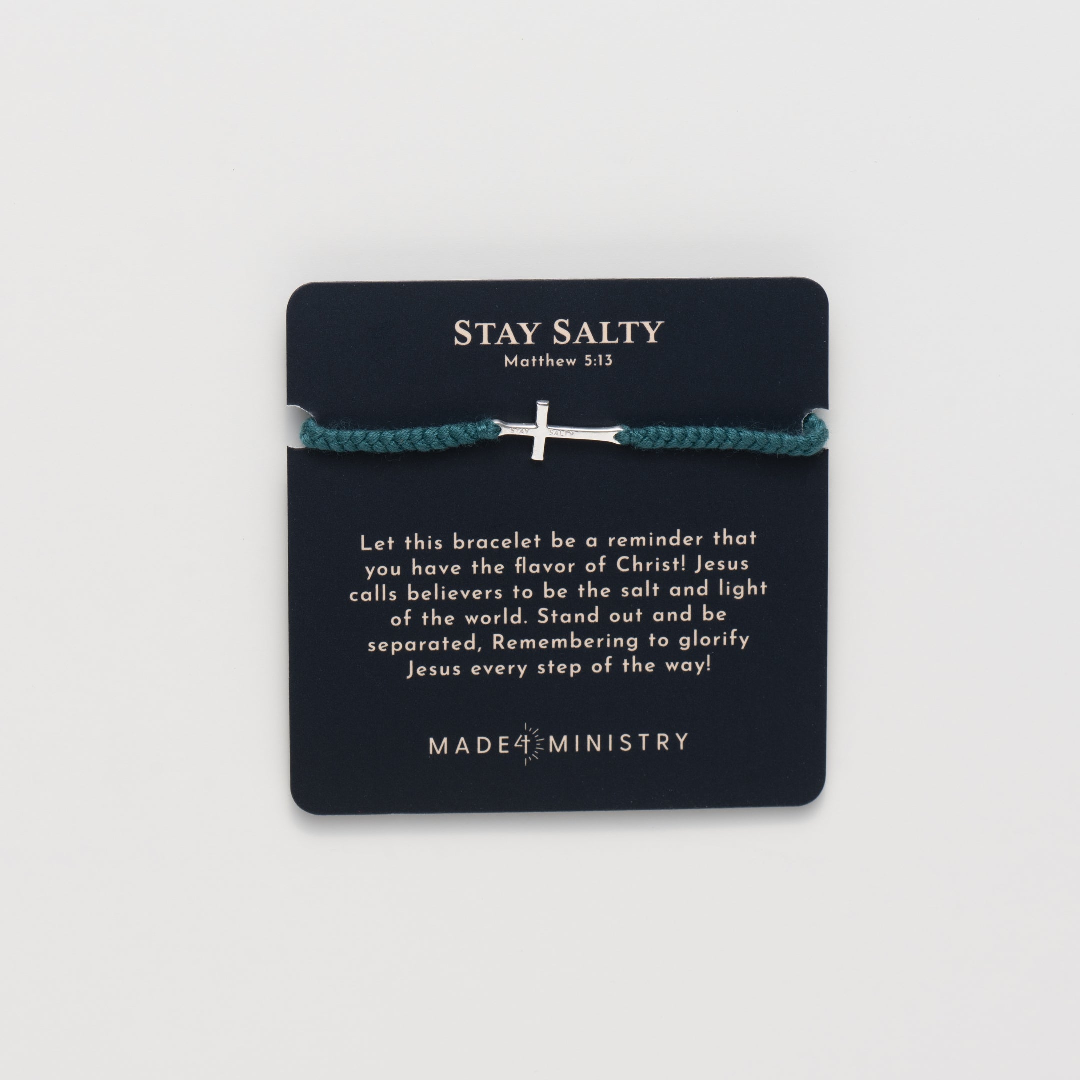 Cross bracelet engraved STAY SALTY set on a naturally dyed azure blue hand-braided, cotton cord friendship bracelet with a  Sterling Silver finish from the Made4Ministry Collection by Rizen Jewelry on a devotion card. 