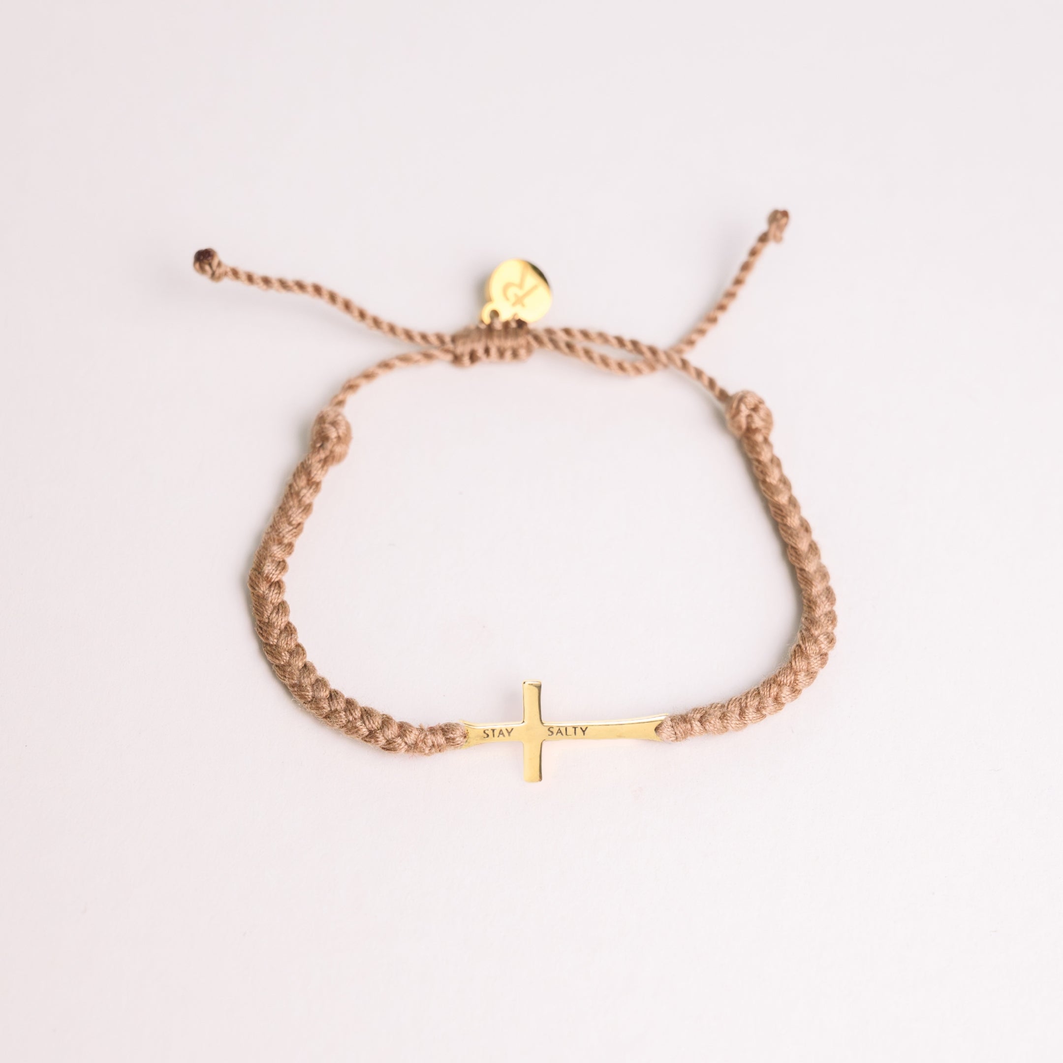 Cross bracelet engraved STAY SALTY set on a naturally dyed khaki hand-braided, cotton cord friendship bracelet with a gold or sterling silver finish from the Made4Ministry Collection by Rizen Jewelry. 