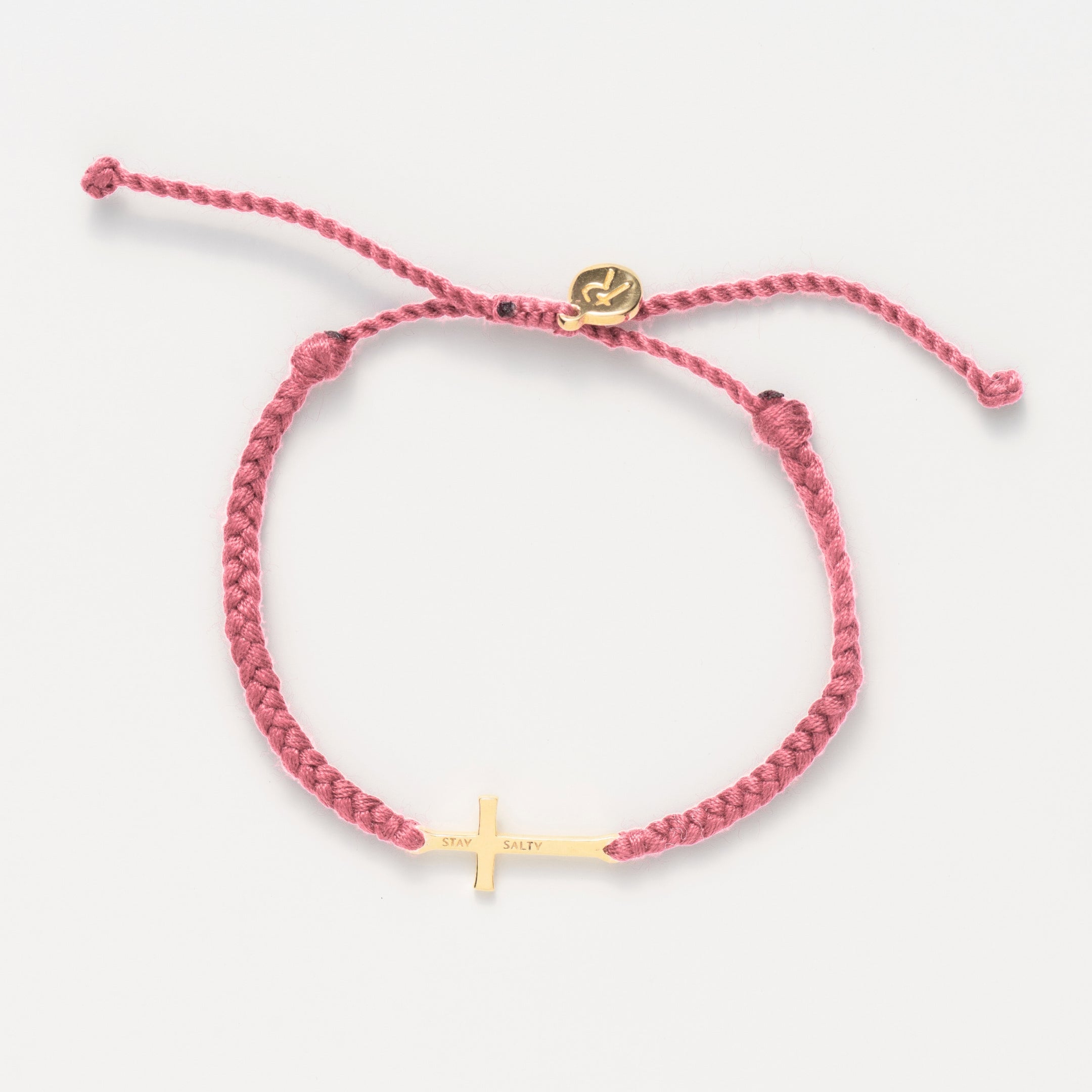 Cross bracelet engraved STAY SALTY set on a naturally dyed pink dusty rose hand-braided, cotton cord friendship bracelet with a gold or sterling silver finish from the Made4Ministry Collection by Rizen Jewelry. 