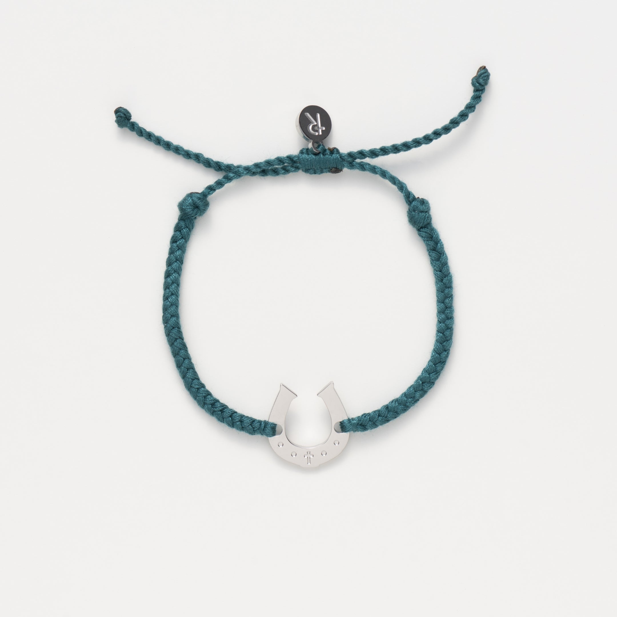 Horseshoe bracelet engraved with a cross set on a naturally dyed azure blue hand-braided, cotton cord friendship bracelet. Available in 18k Gold and Sterling Silver finish.