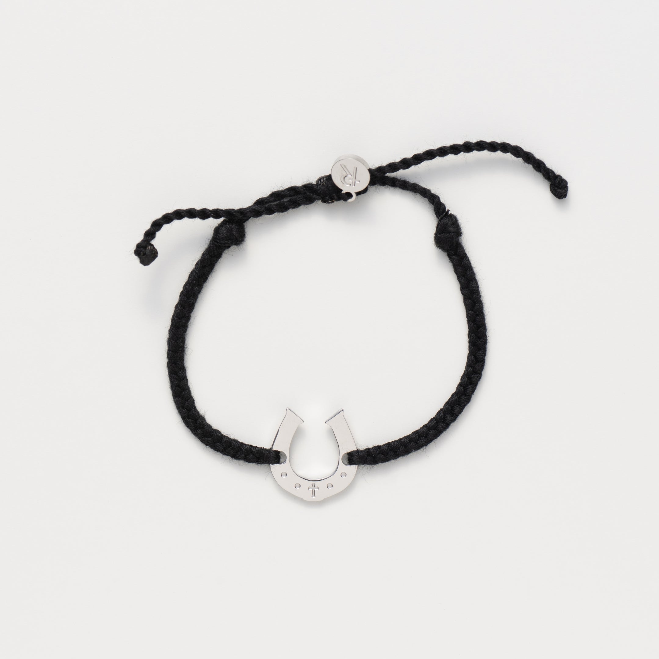 Horseshoe bracelet engraved with a cross set on a naturally dyed black hand-braided, cotton cord friendship bracelet. Available in 18k Gold and Sterling Silver finish.