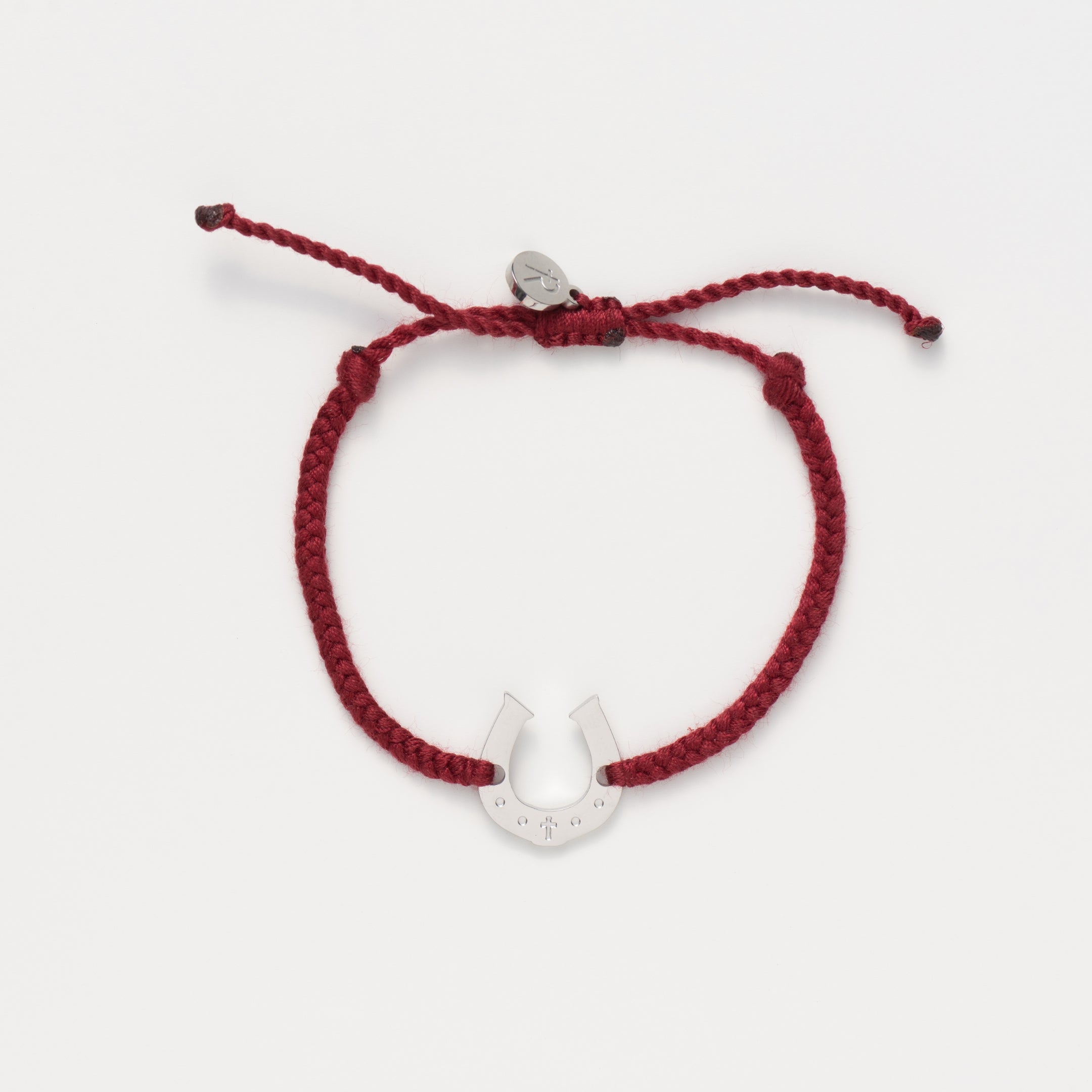 Horseshoe bracelet engraved with a cross set on a naturally dyed garnet red hand-braided, cotton cord friendship bracelet. Available in 18k Gold and Sterling Silver finish. Designed by Rizen Jewelry for the Made4Ministry Collection. 