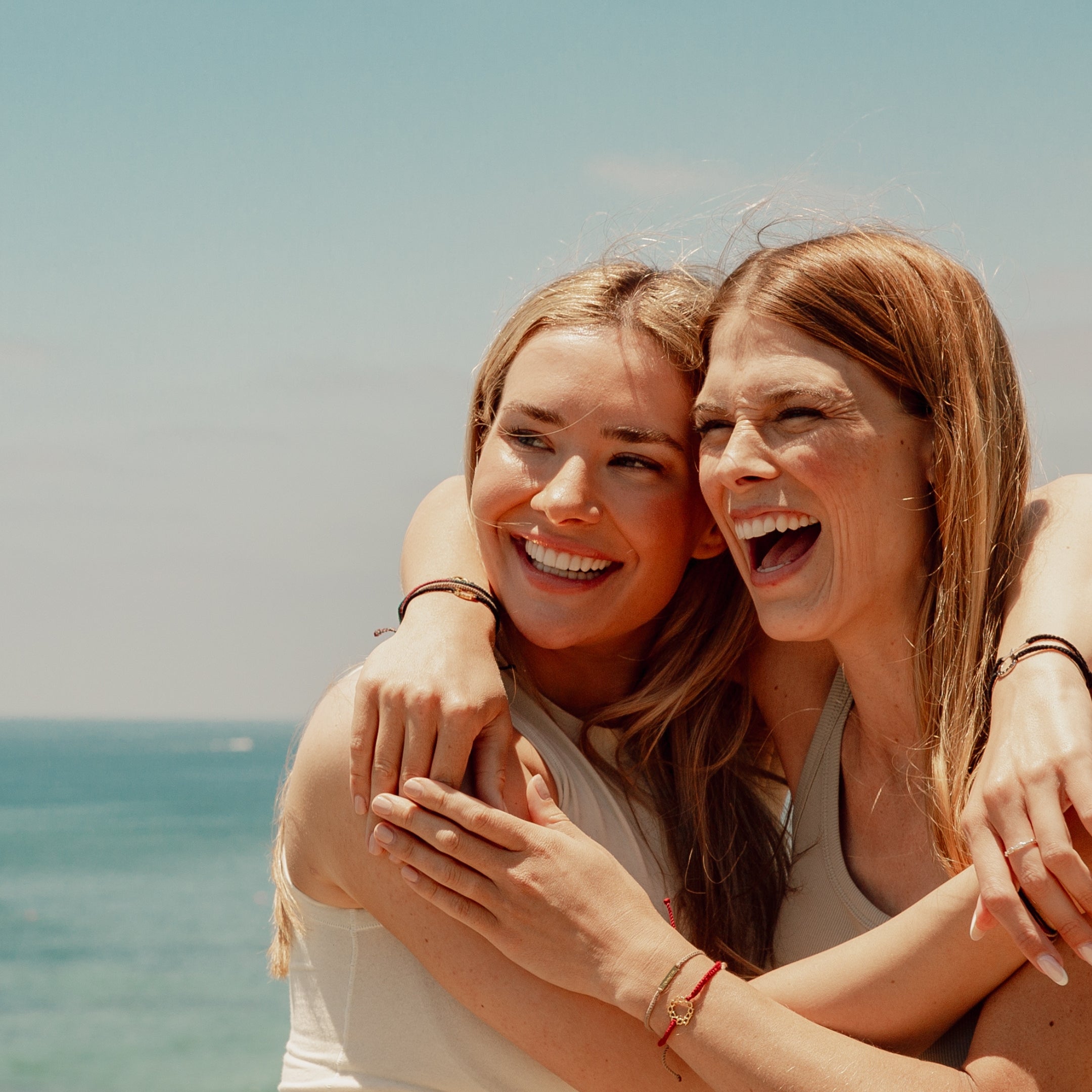 Friends hugging and laughing wearing the inspirational Made4Ministry friendship bracelets  by Rizen Jewelry. 