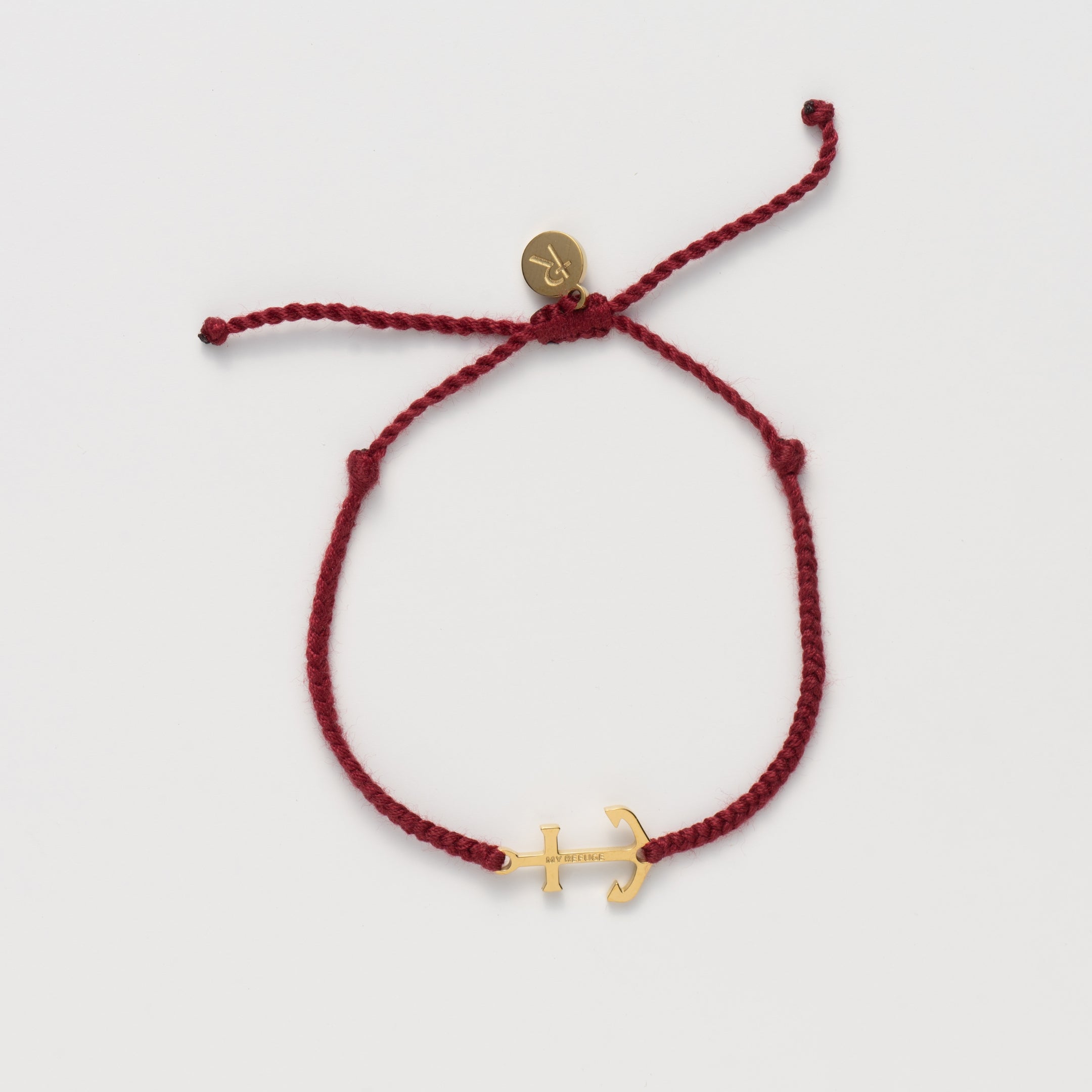Classic nautical anchor bracelet, delicately engraved with the inscription “MY REFUGE,” hand-braided from naturally dyed garnet red cotton cord. Available in 18k gold or sterling silver finish.