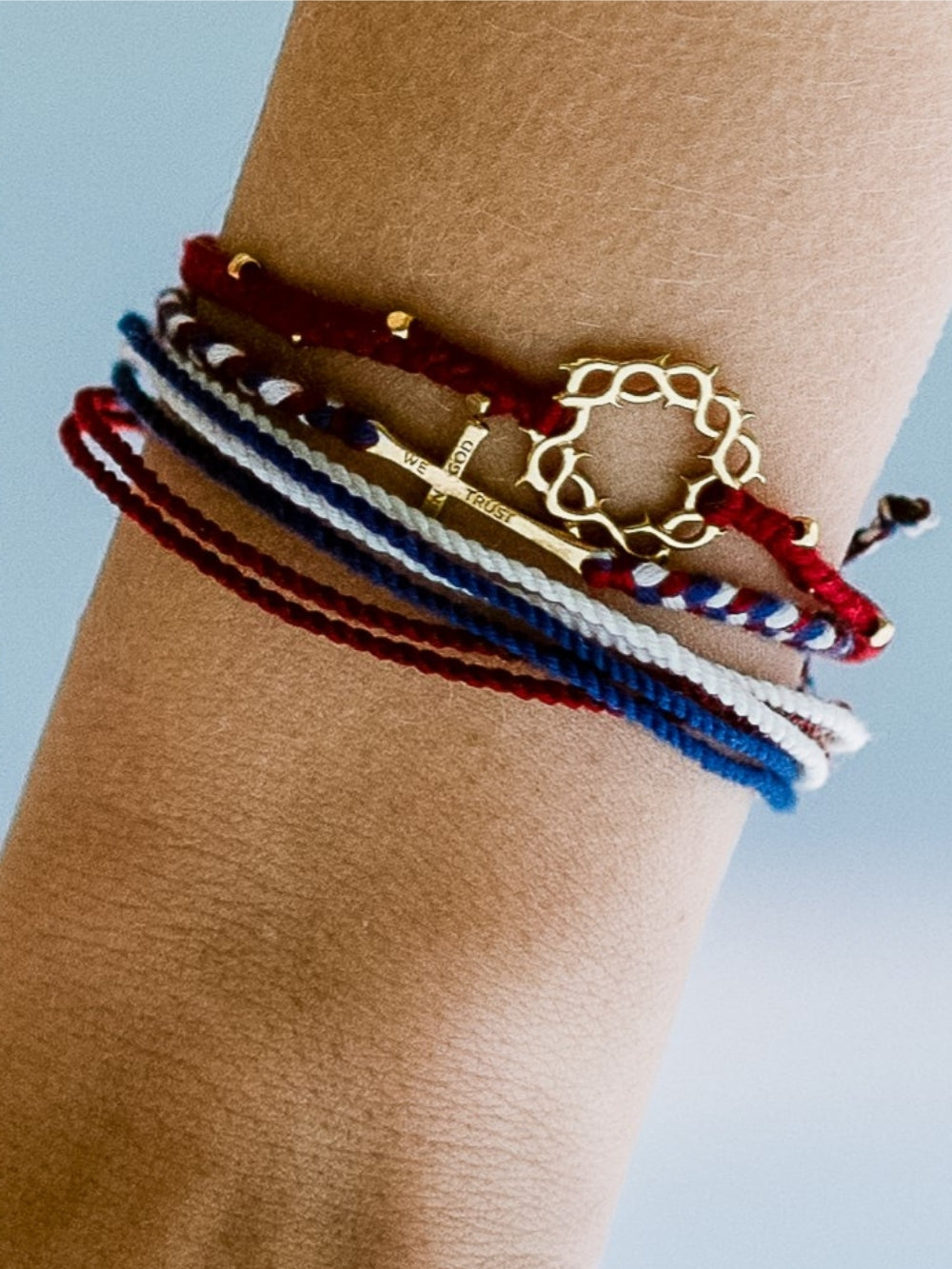 Female Christian model wearing the We Trust In God Cross Braided Bracelet by Made for Ministry and Rizen Jewelry, licensed by Freedom 250. 