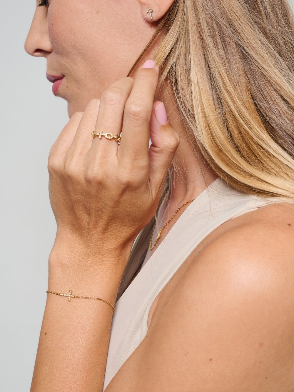 Female model wearing the Delicate Cross Chain Breaker Bracelet, an 18k gold-plated pavé cross bracelet resting on her wrist by Rizen Jewelry