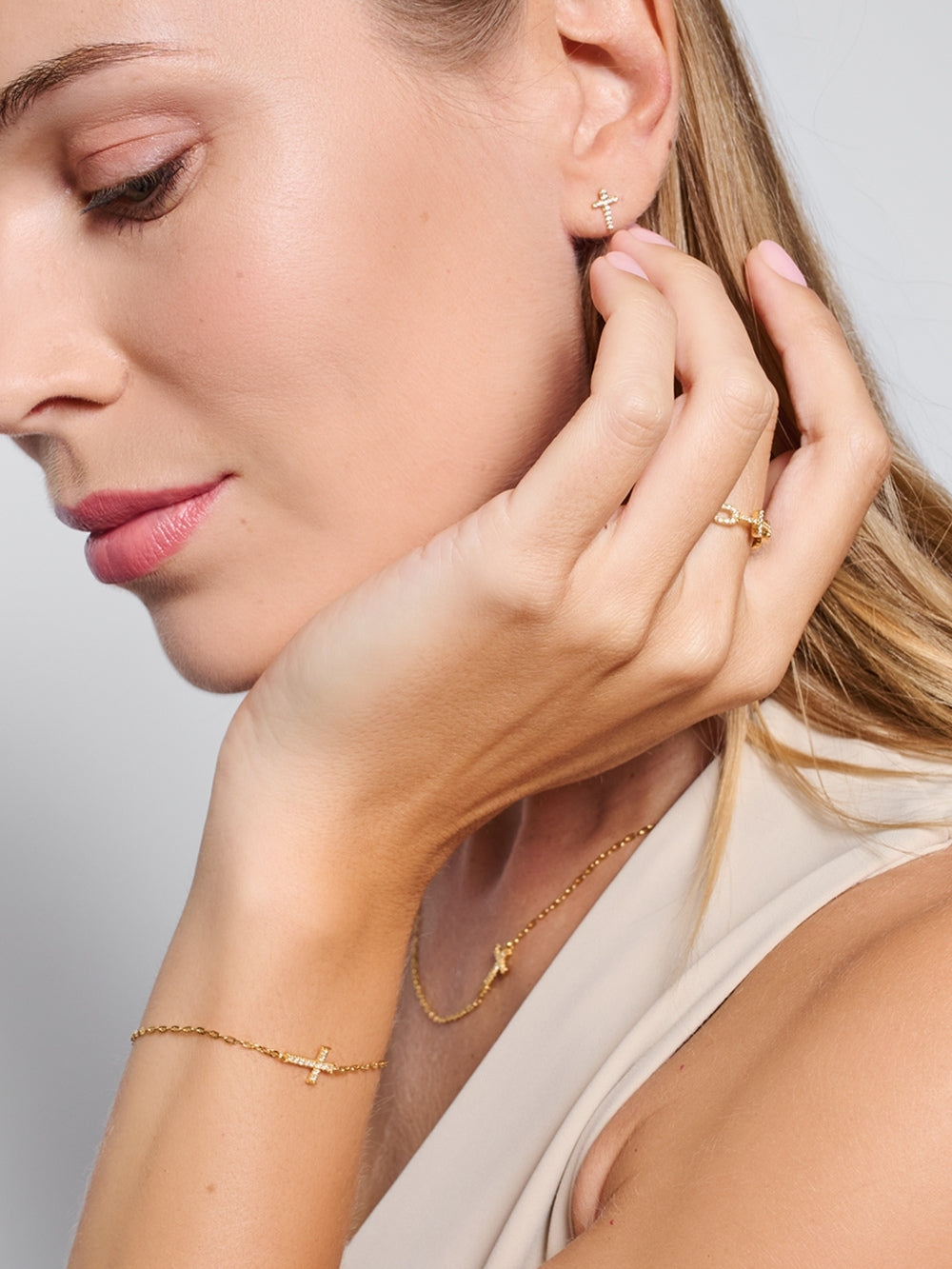 Female model wearing the Delicate Cross Chain Breaker Bracelet, an 18k gold-plated pavé cross bracelet resting on her wrist by Rizen Jewelry