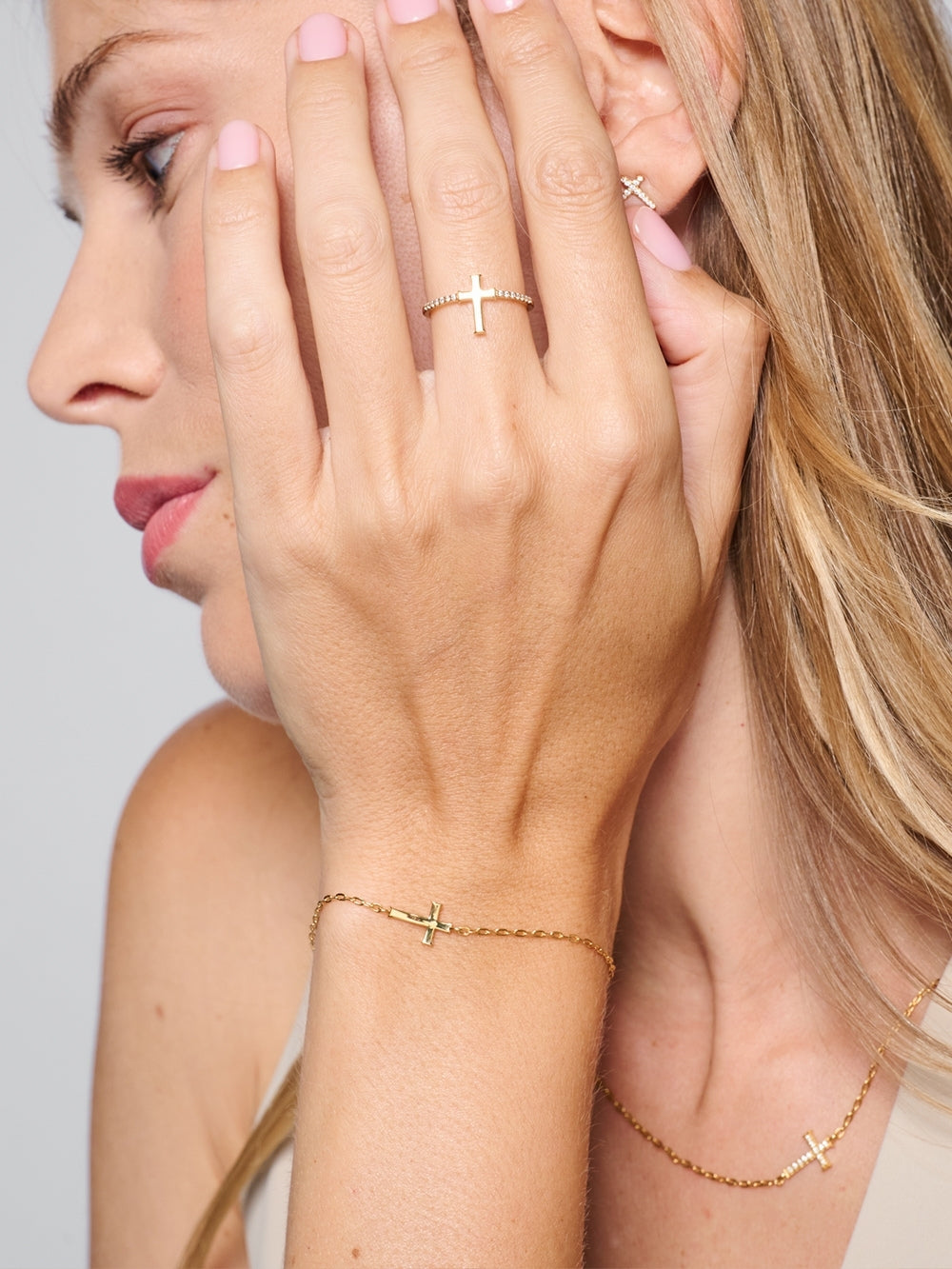 Female model wearing the Delicate Cross Chain Breaker Bracelet, with the high polish backside of the cross shown resting on her wrist by Rizen Jewelry