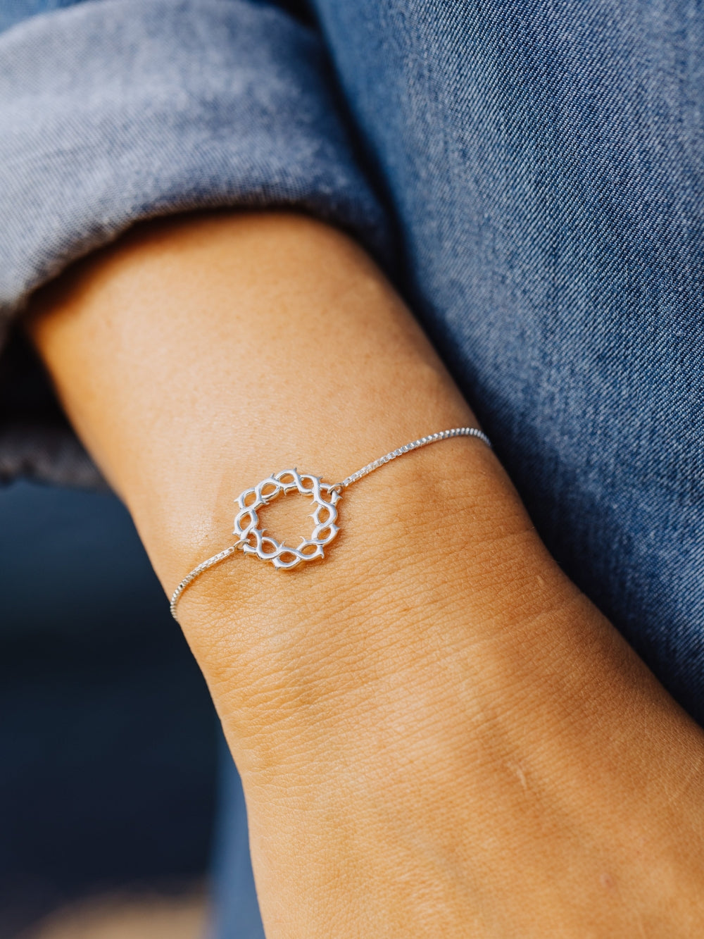 Women's Christian jewelry model is wearing the Crown of thorns bracelet in sterling silver from the Insignia collection. A timeless baptism gift by Rizen Jewelry.