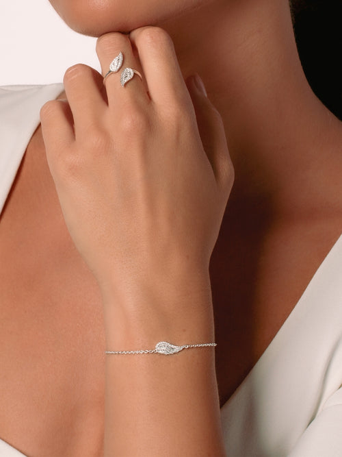 Women's Christian jewelry model is wearing the Divine wings bracelet in sterling silver alongside a ring from the Insignia collection. Inspirational gift for any occasion by Rizen Jewelry.
