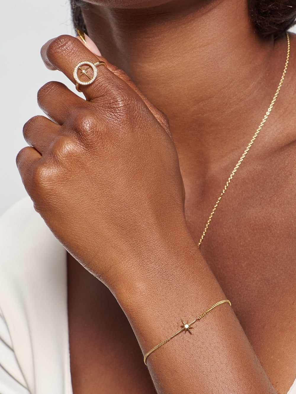 Model wearing the Adoring Star Bracelet on her wrist, styled with the Adoring Star Compass Ring both designed by Rizen Jewelry. 